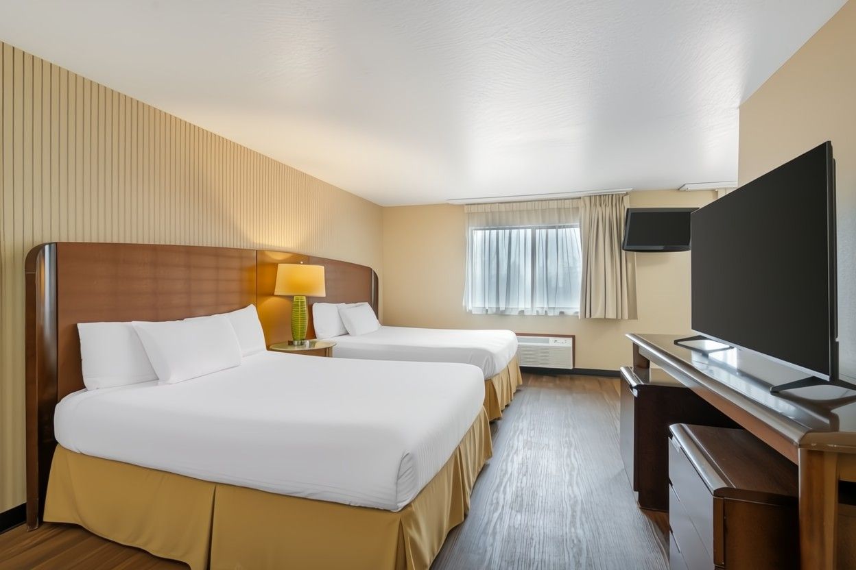image Two queen pillow-top beds with white linens.