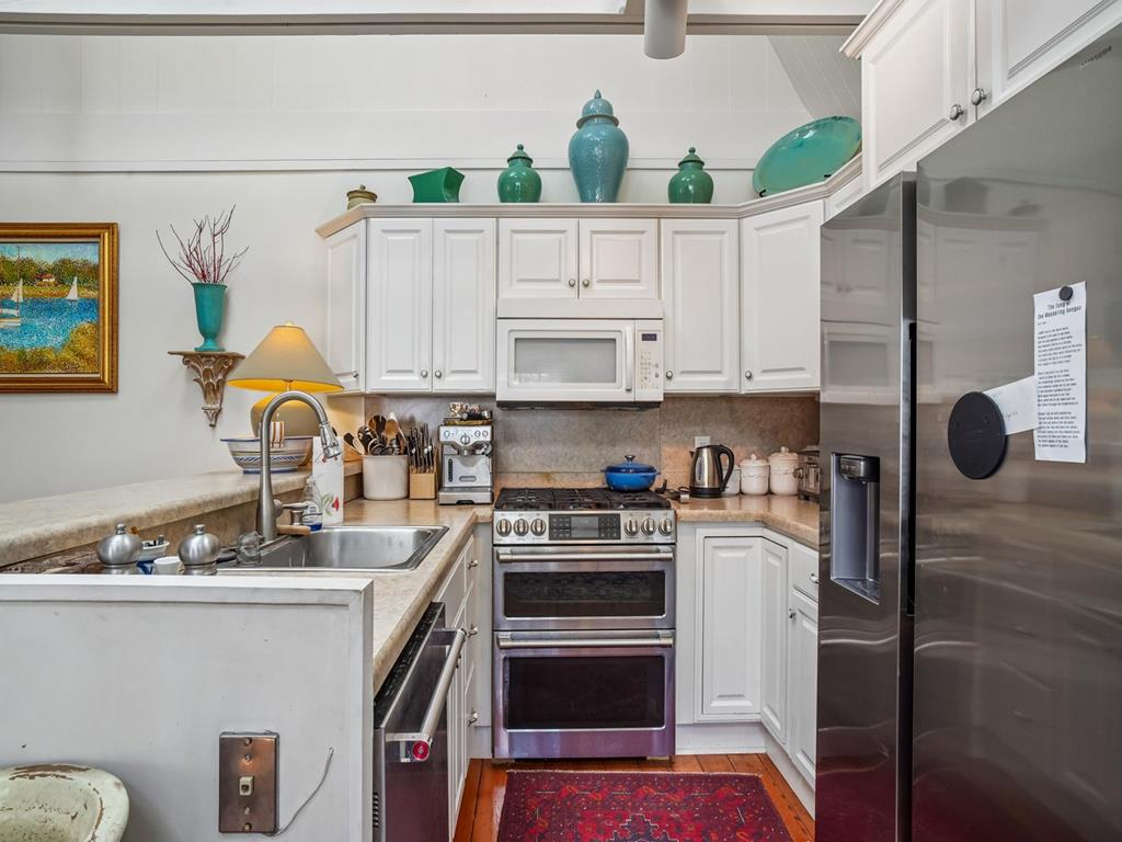 image White cabinetry and stainless steel appliances fill the kitchen — refrigerator, stove, oven, dishwasher, and microwave all included