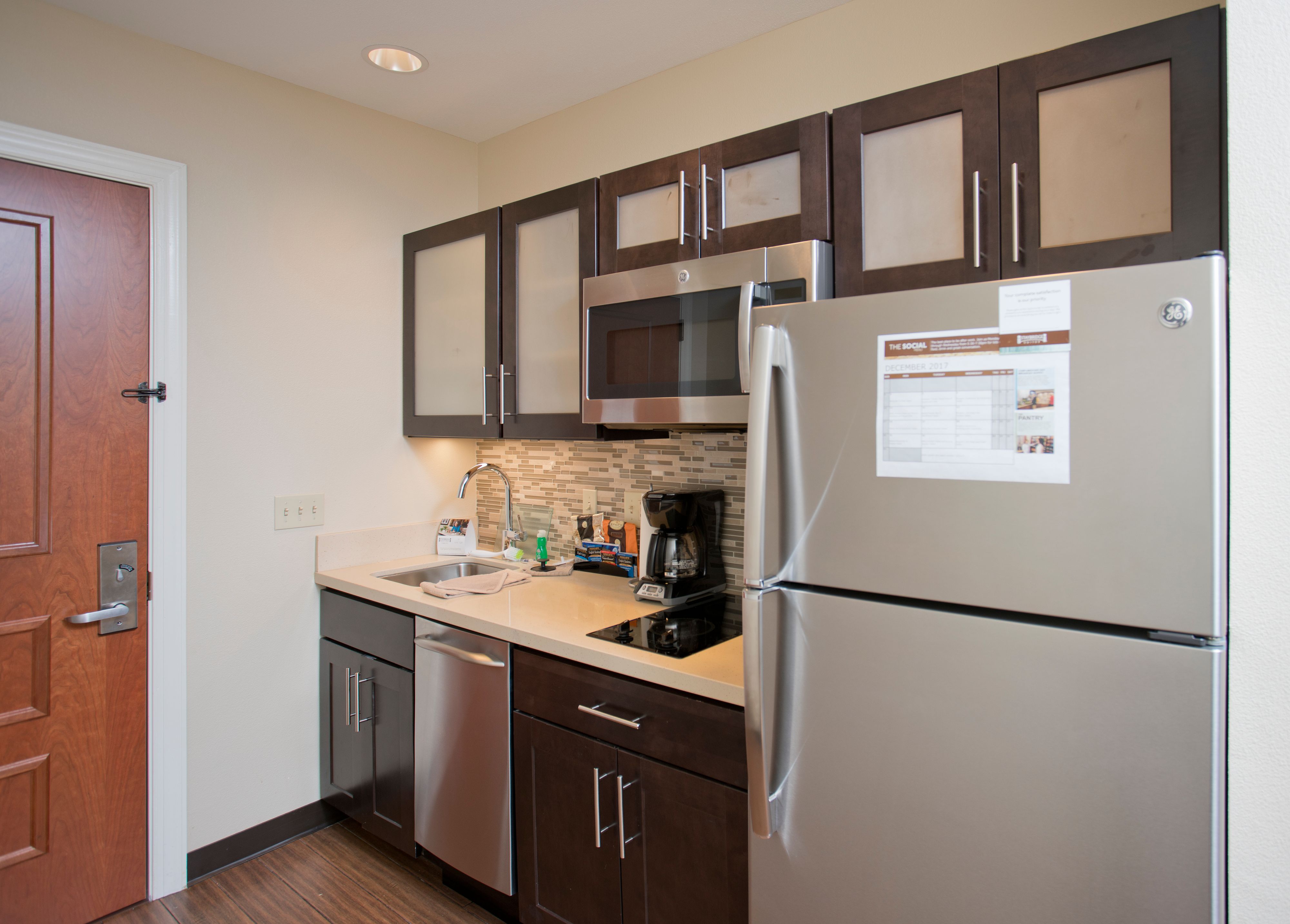 image Fully equipped kitchen featuring dark cabinetry and stainless steel appliances.