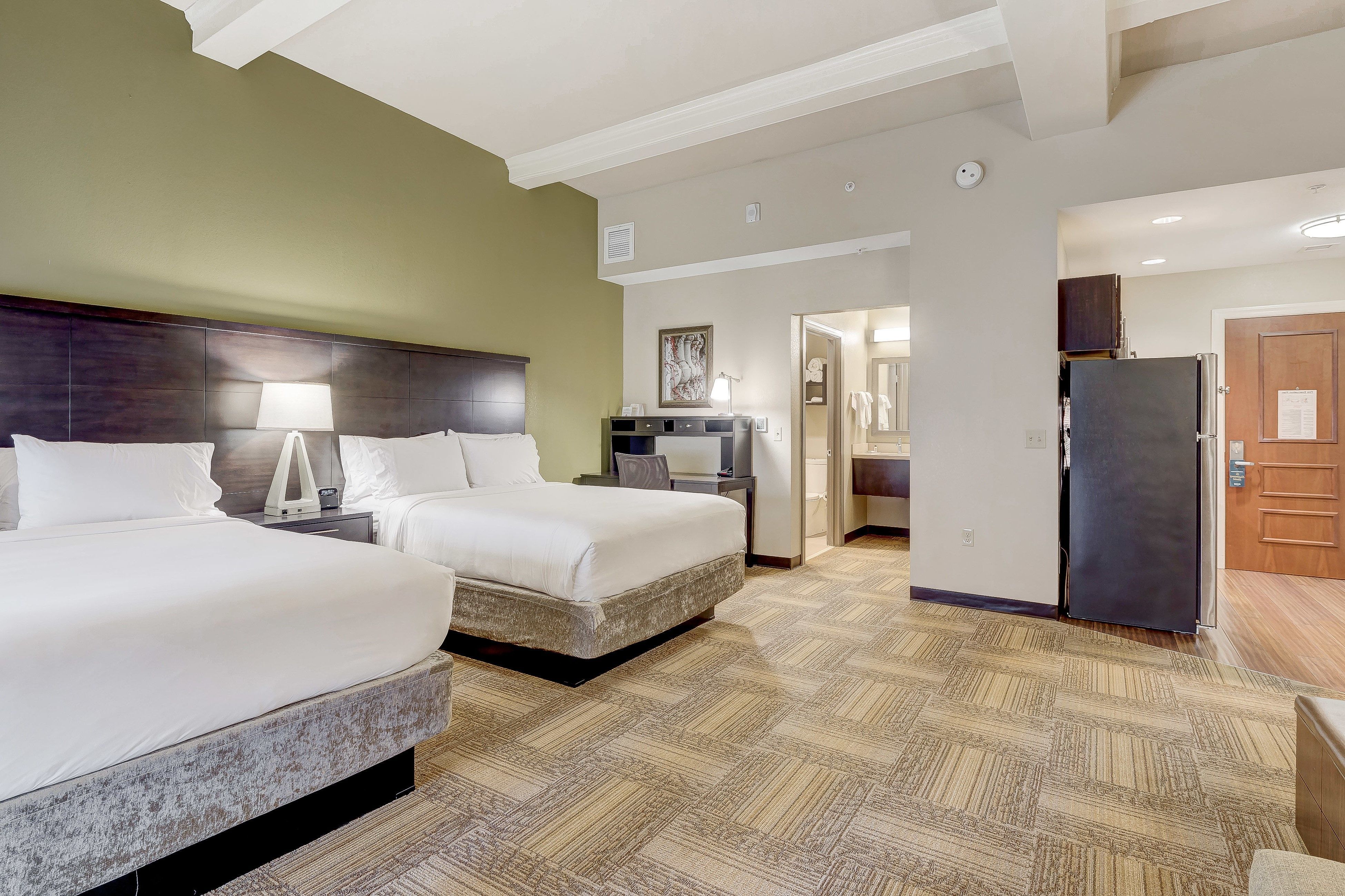 image Spacious hotel suite featuring two comfortable beds and modern decor.