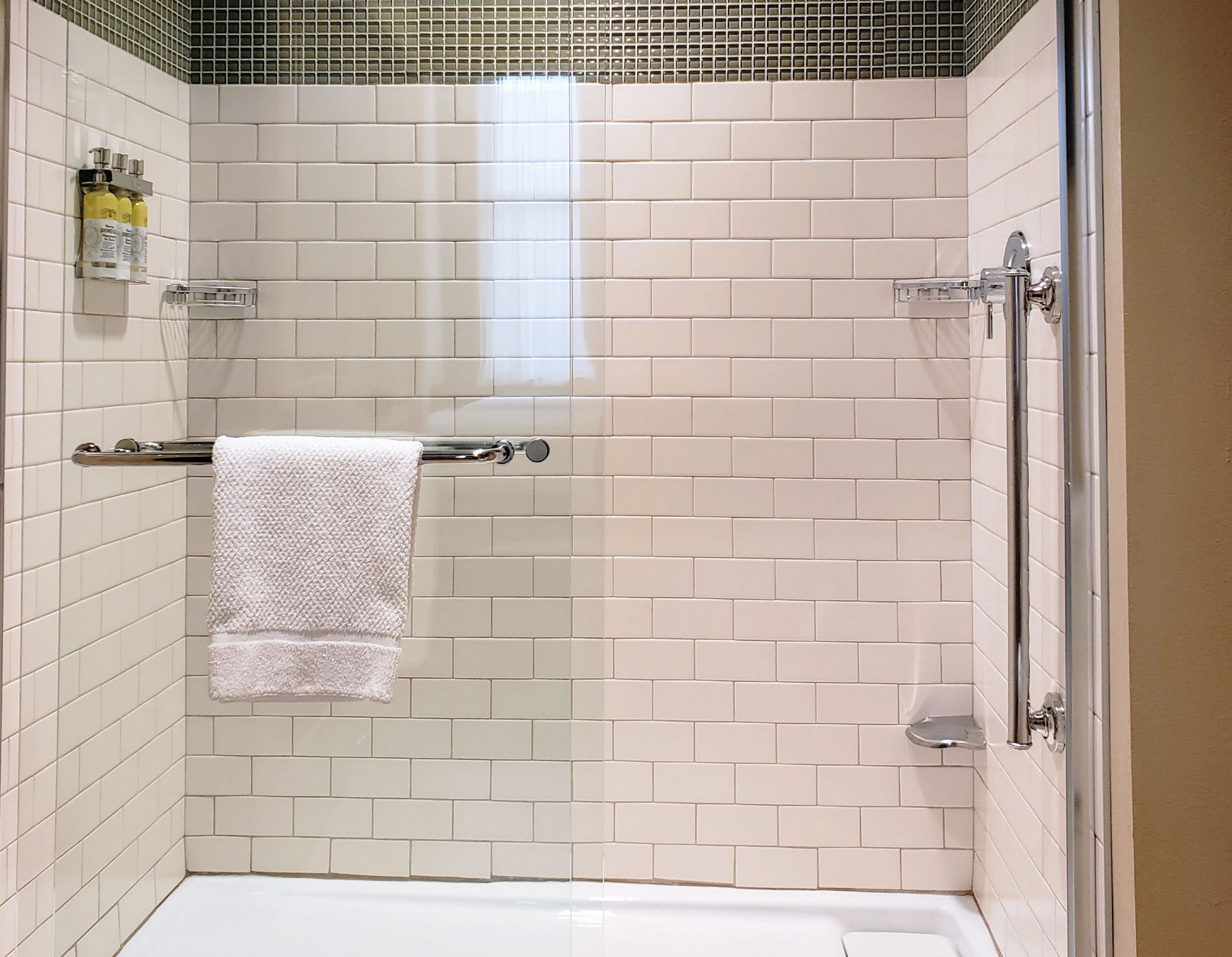 image Spacious walk-in shower with tiled walls and convenient grab bars.