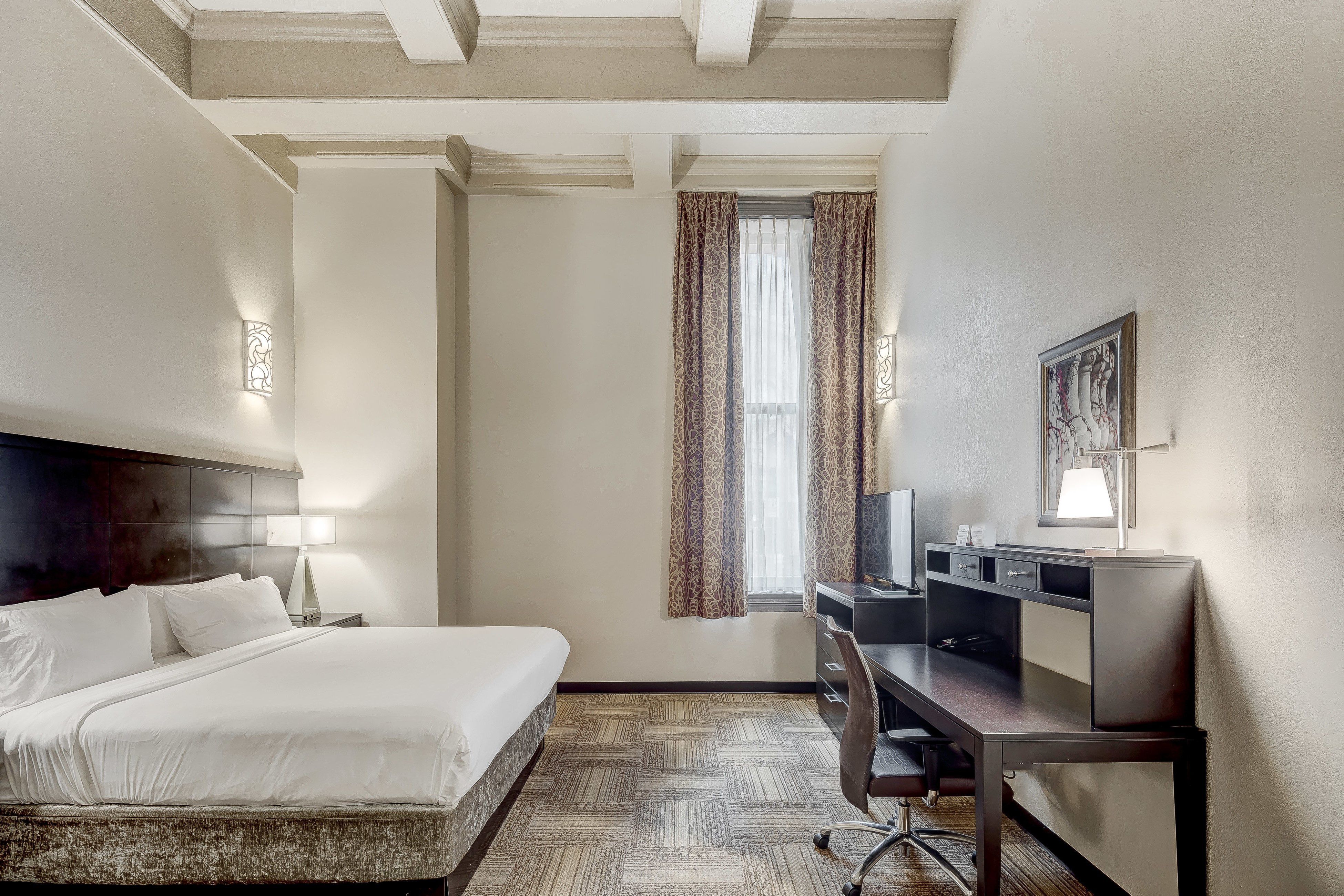 image Spacious hotel suite featuring a plush bed and elegant decor.