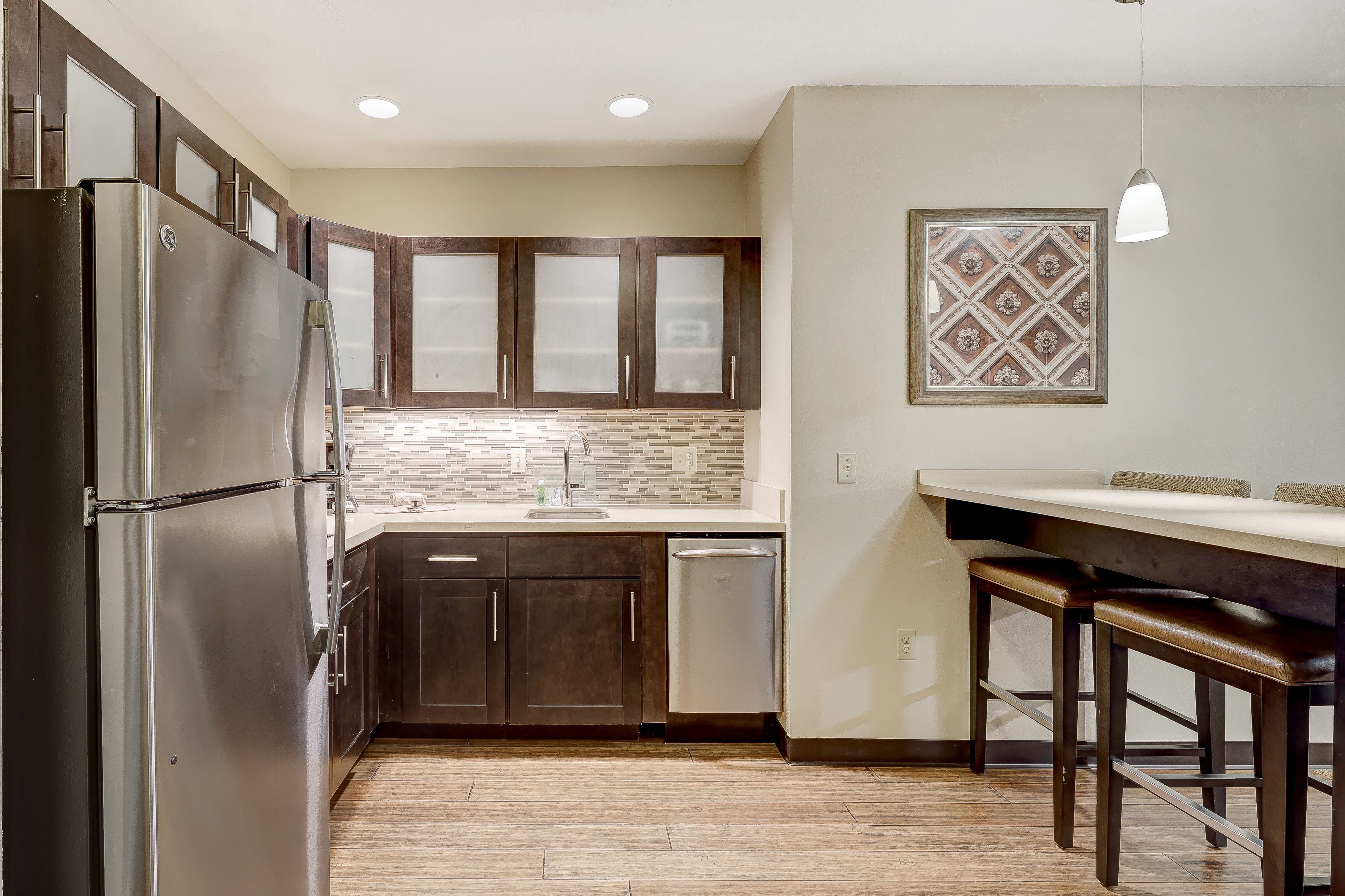 image Functional kitchen layout showcasing cabinetry and modern backsplash.