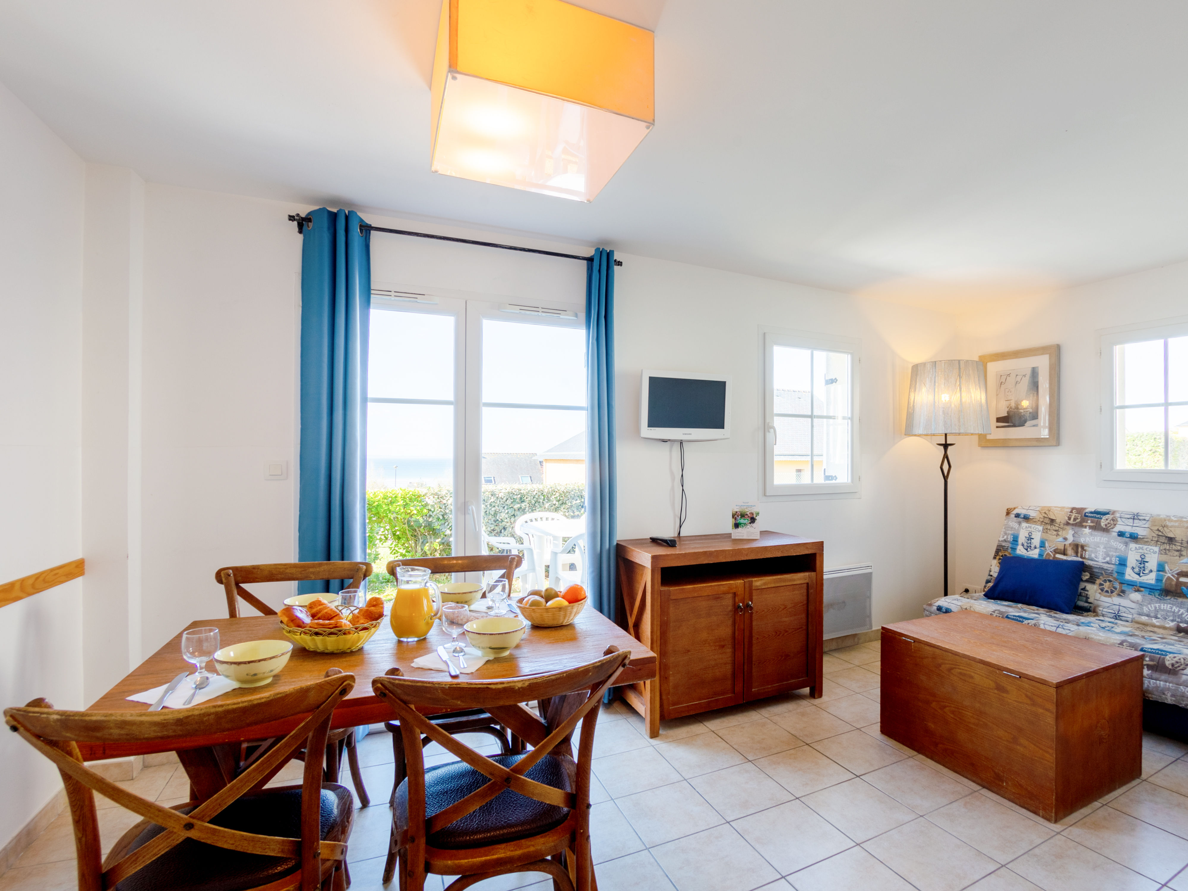 image Dining table for four — windows bring in natural light and a glimpse of the sea beyond