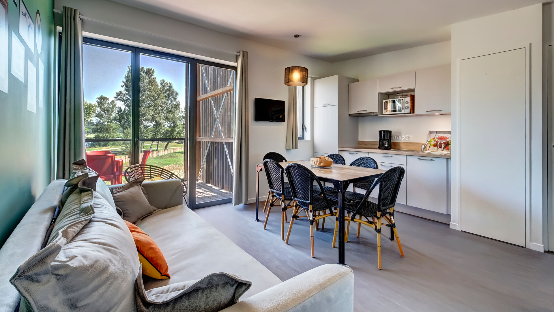 image Large picture windows flood the open living area with natural light — the sofa bed and flat-screen TV make this a room you'll actually use