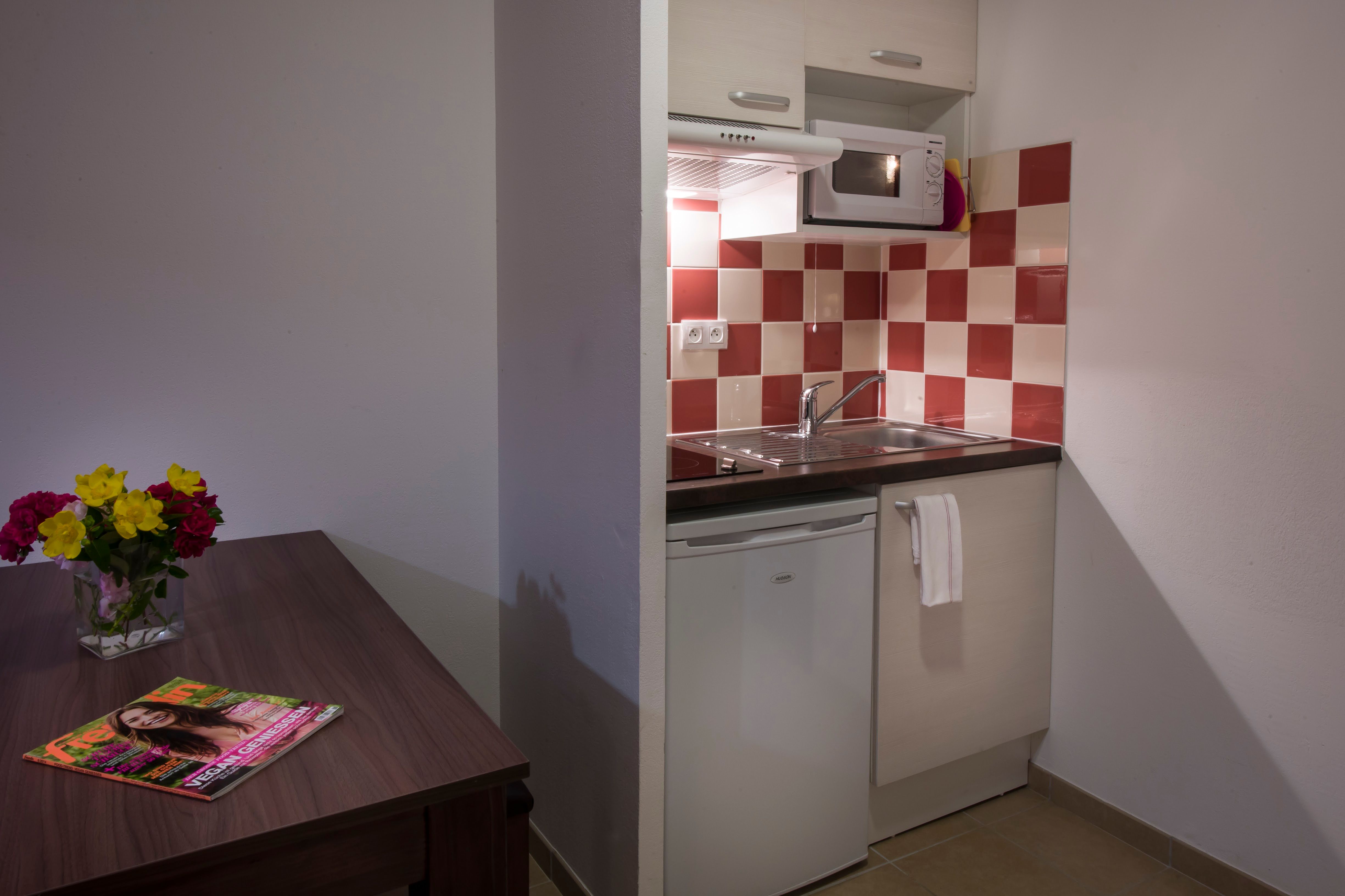 image Kitchenette with ceramic hob, microwave, refrigerator, coffee machine, and kettle