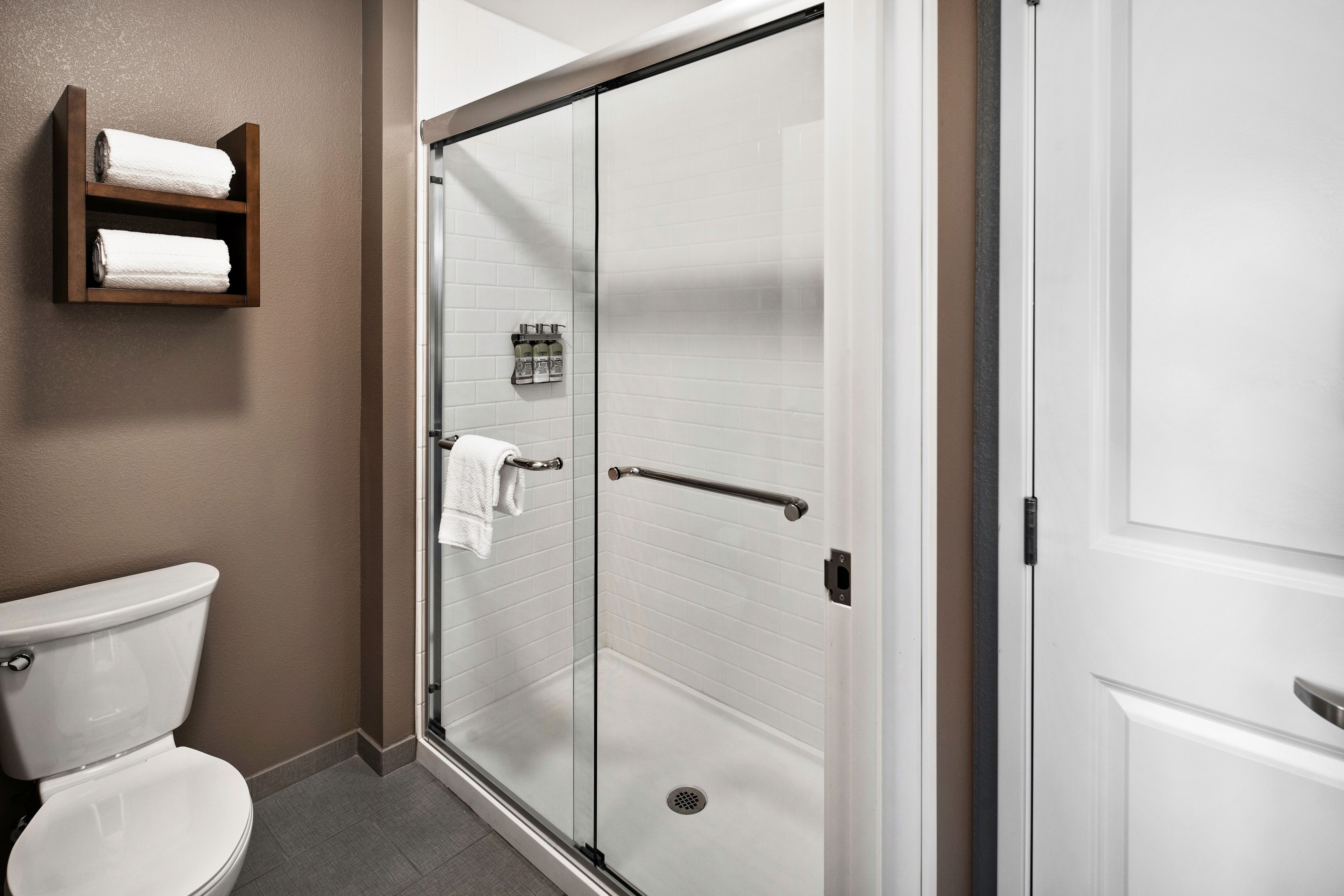 image Modern bathroom with glass shower and white towels on display.
