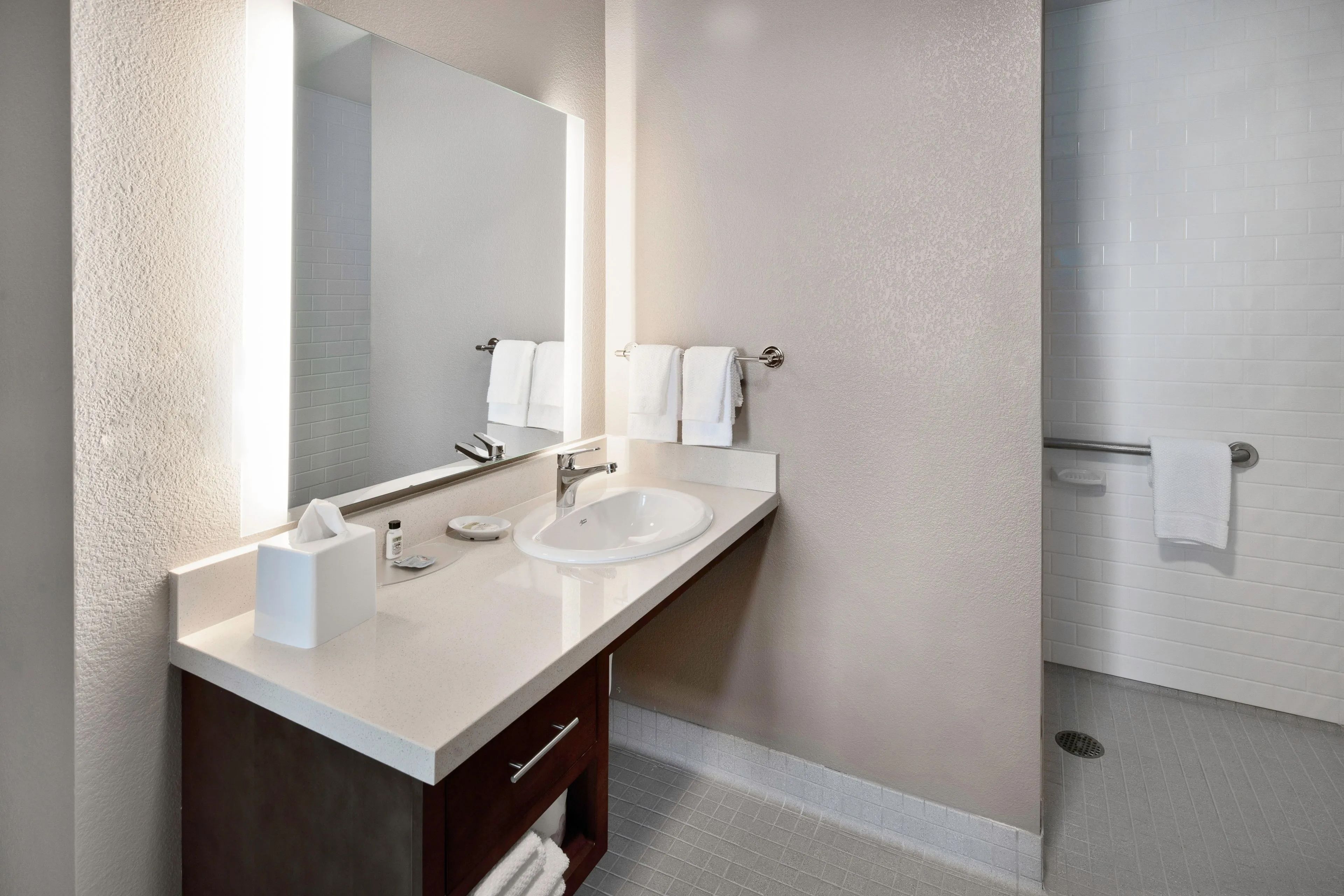 image Modern bathroom for convenience with vanity, towels, and toiletries.