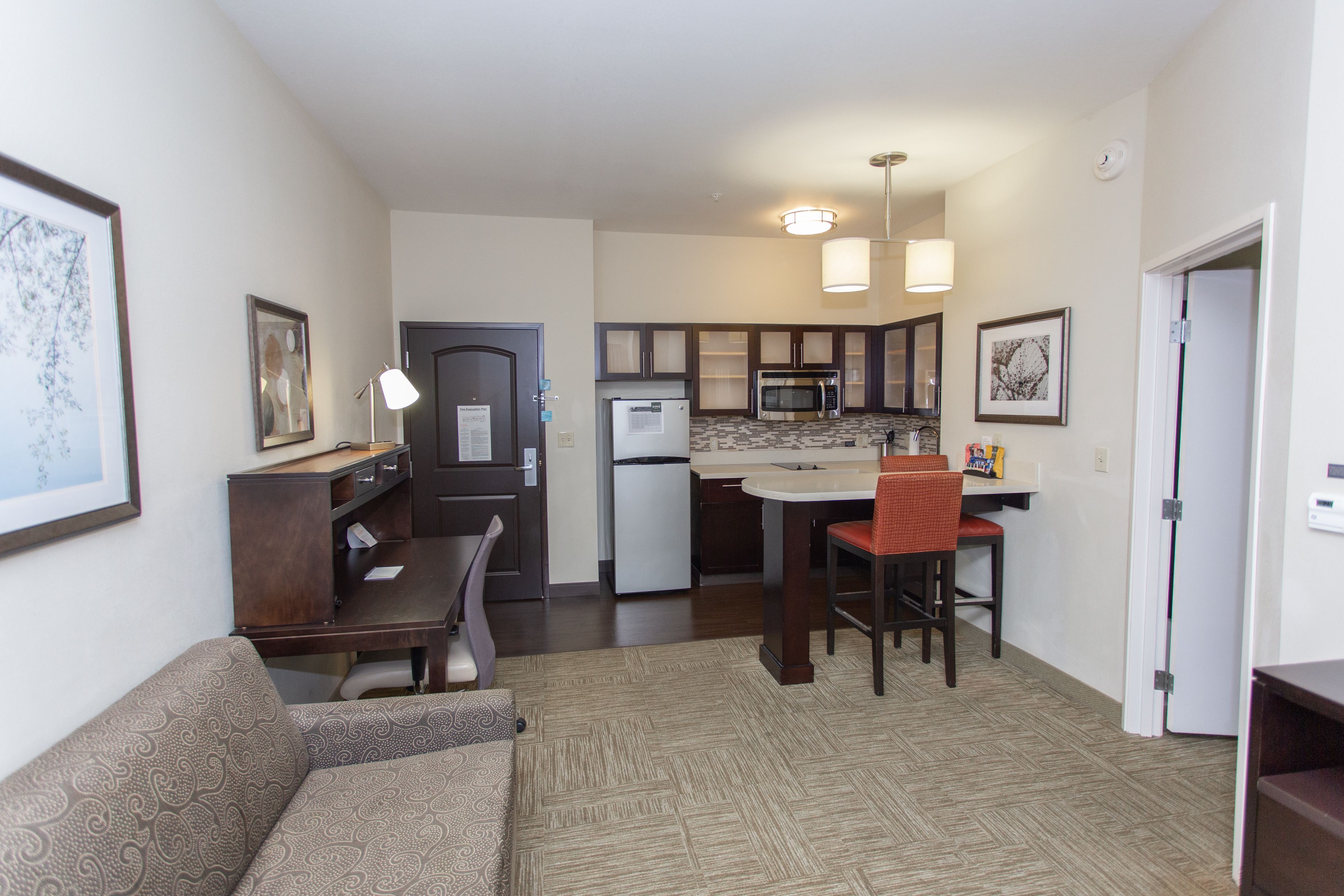 image Open living area with sofa, desk, and kitchen.