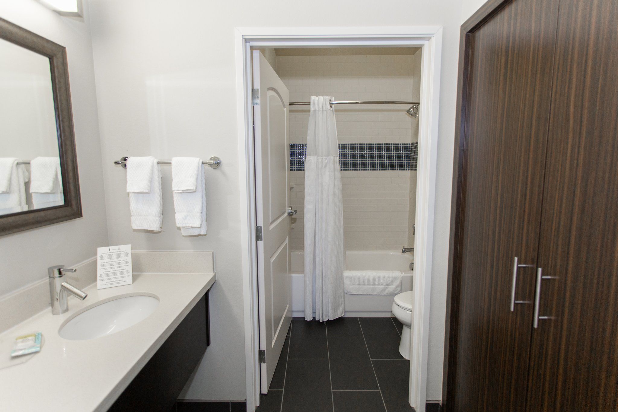 image Accessible bathroom with sink, mirror, towels, and tub.