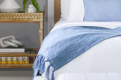 King bed with layered textiles and handwoven rattan accents — your private retreat after a day on the championship courses