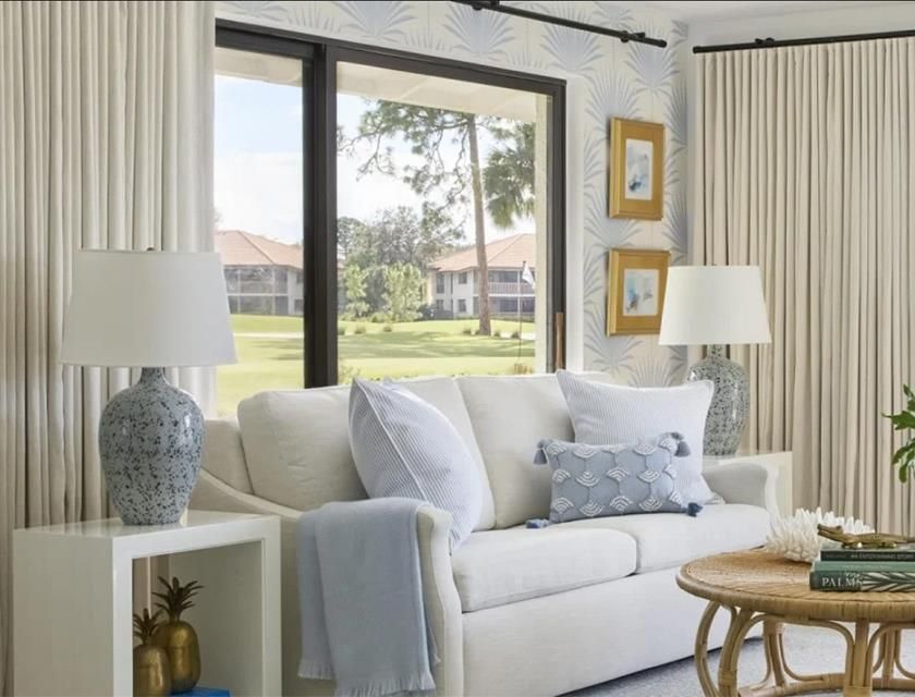image Open-plan living room with 65" LCD TV, pull-out sofa bed, and a coastal palette of whites, blues, and lacquered wood