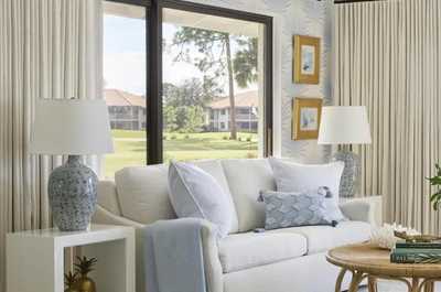 Open-plan living room with 65" LCD TV, pull-out sofa bed, and a coastal palette of whites, blues, and lacquered wood