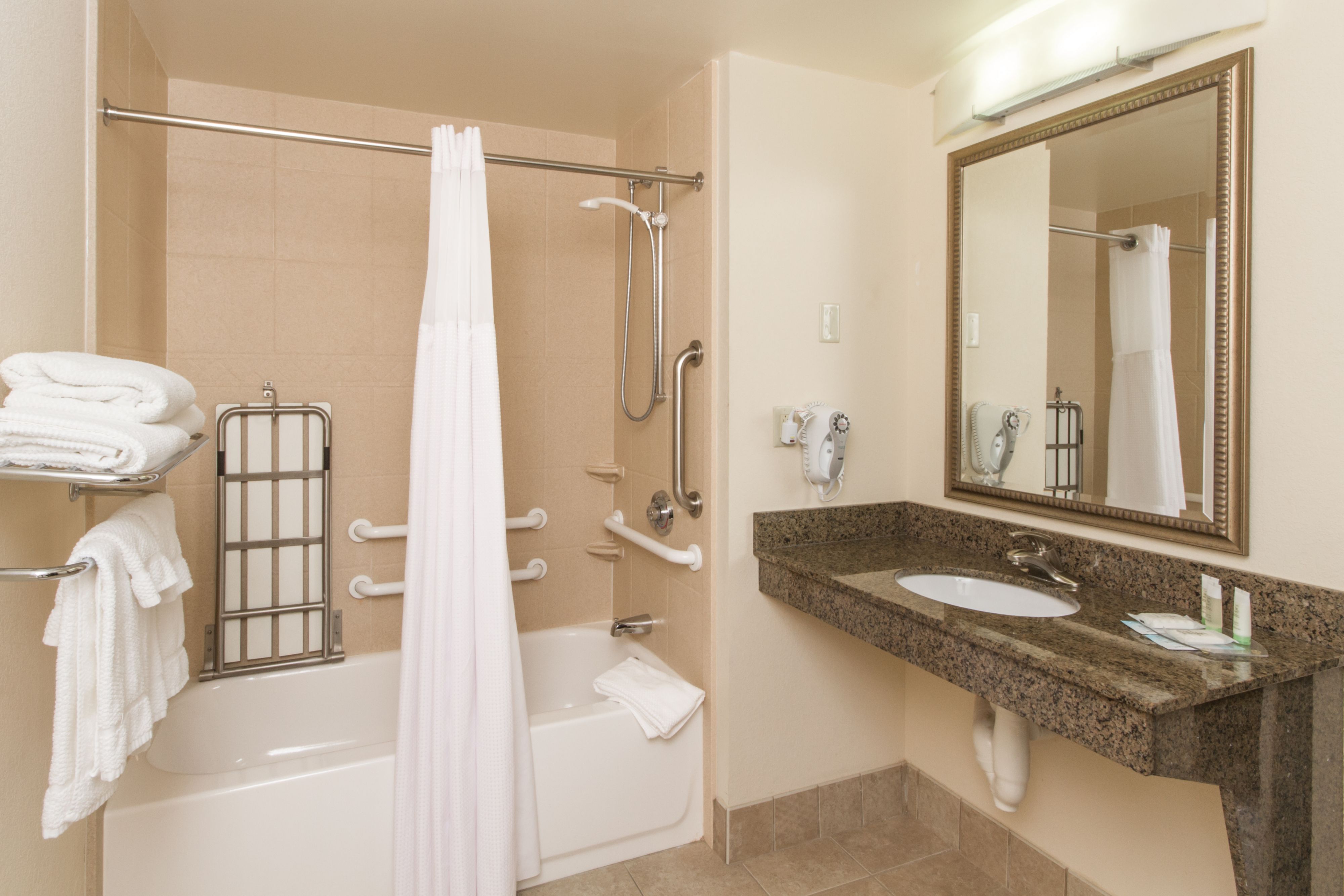 image Accessible bathroom featuring a bathtub with shower curtain and sink.