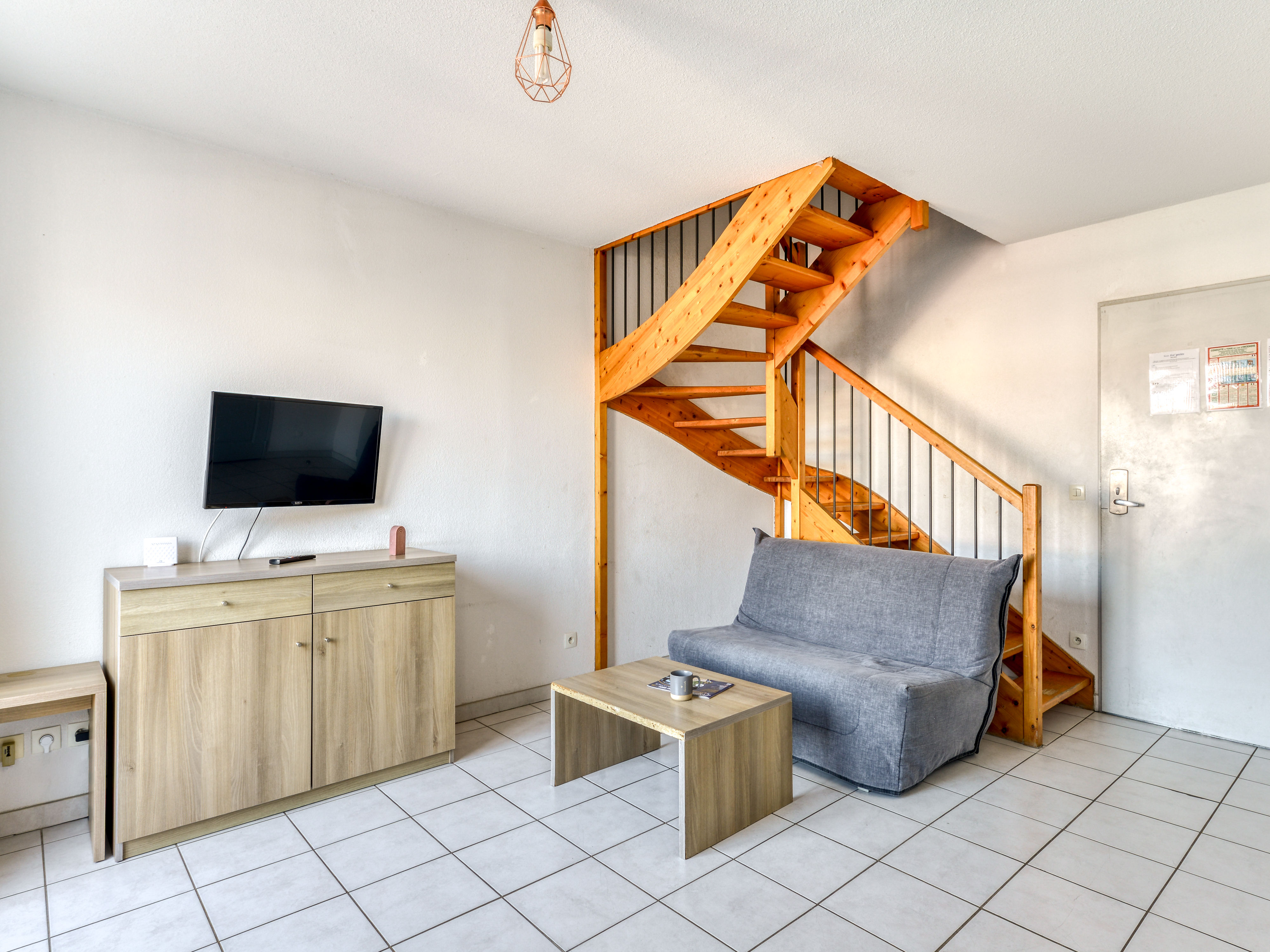 image Airy living room with grey sofa bed (sleeps 2) and flat-screen TV — all on the lower level