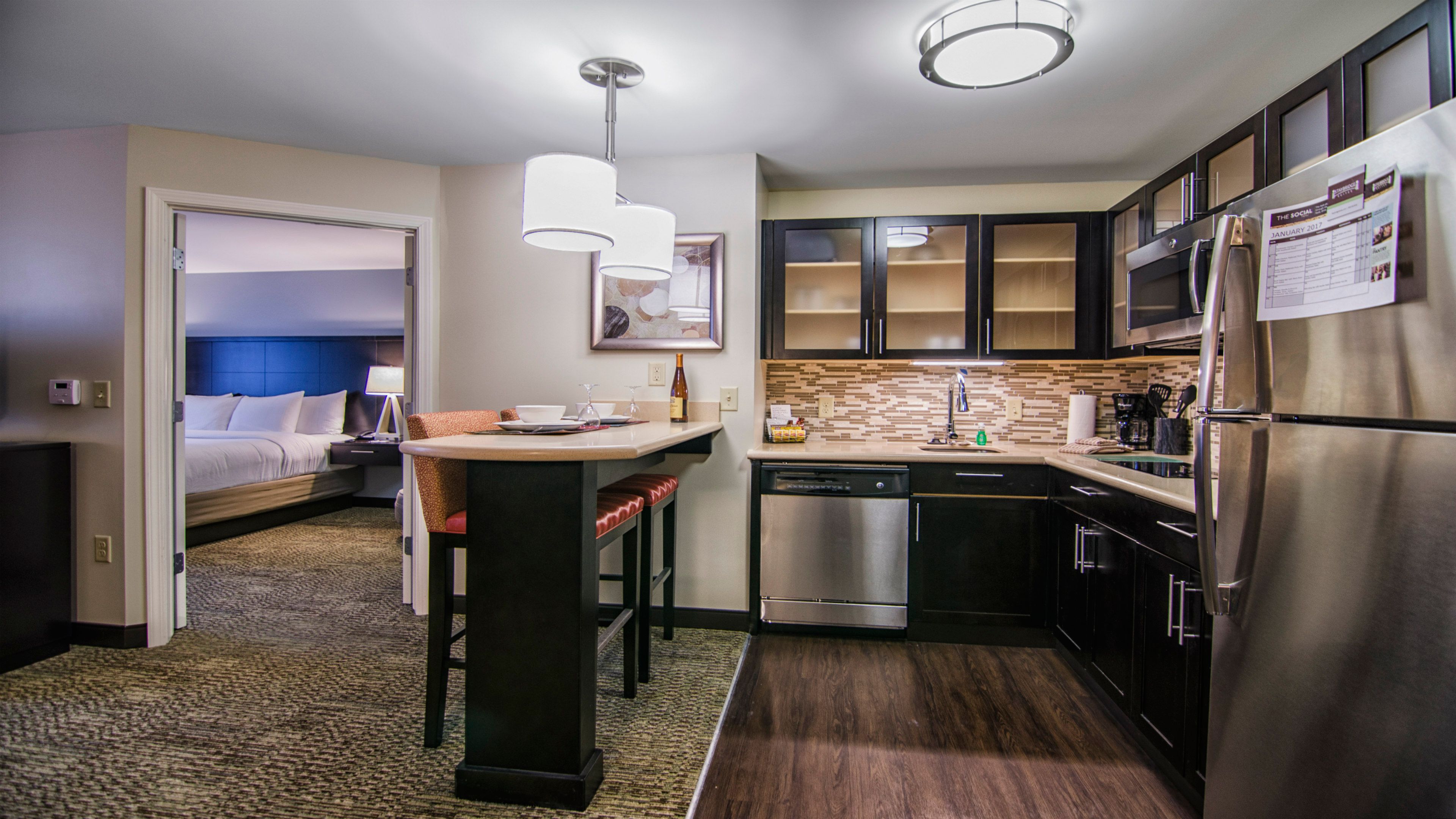 image Modern kitchen with dark cabinetry, bar seating, and full stainless steel appliances.