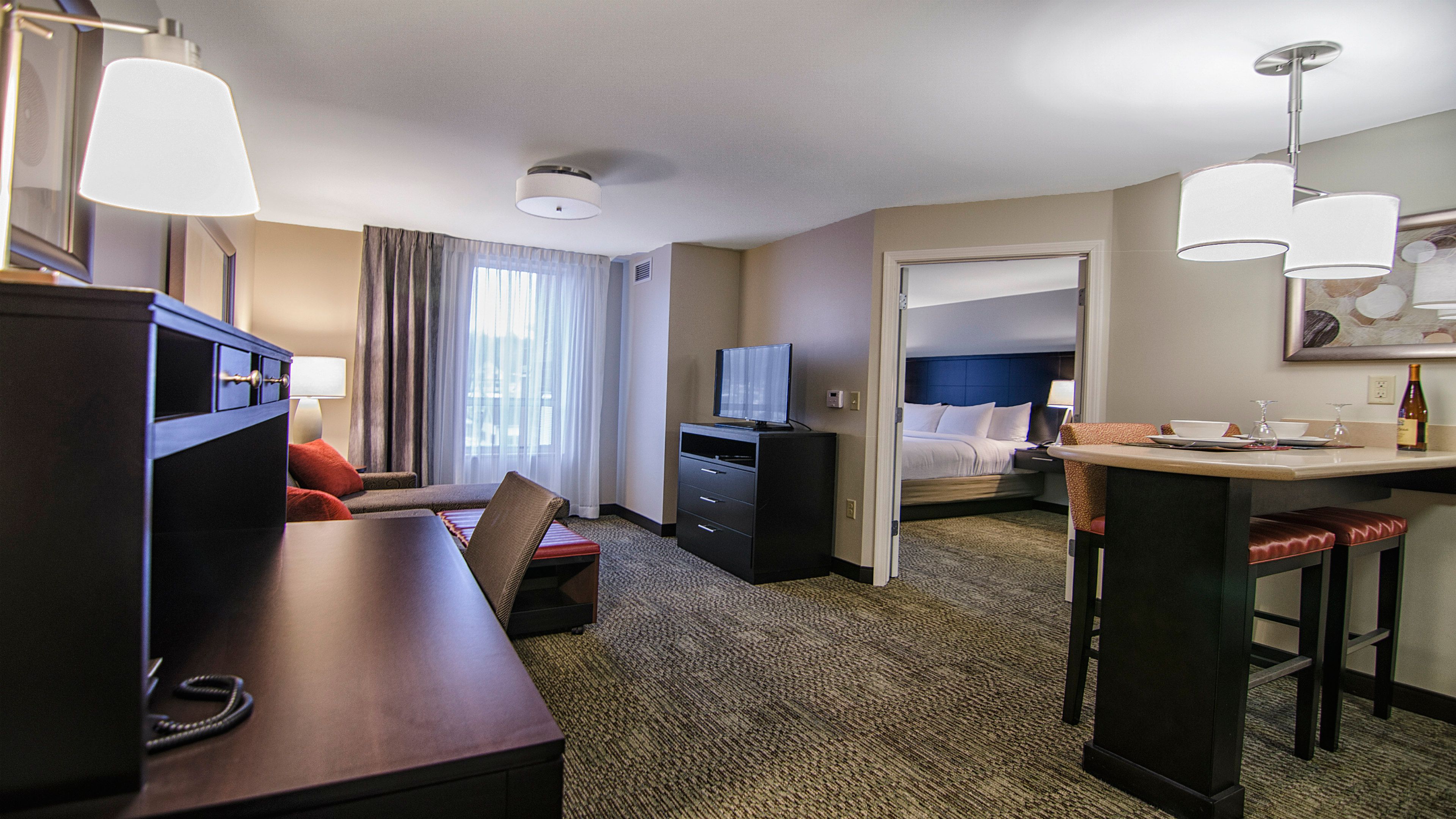 image Open living area with comfortable sofa, flat-screen TV, and work desk.