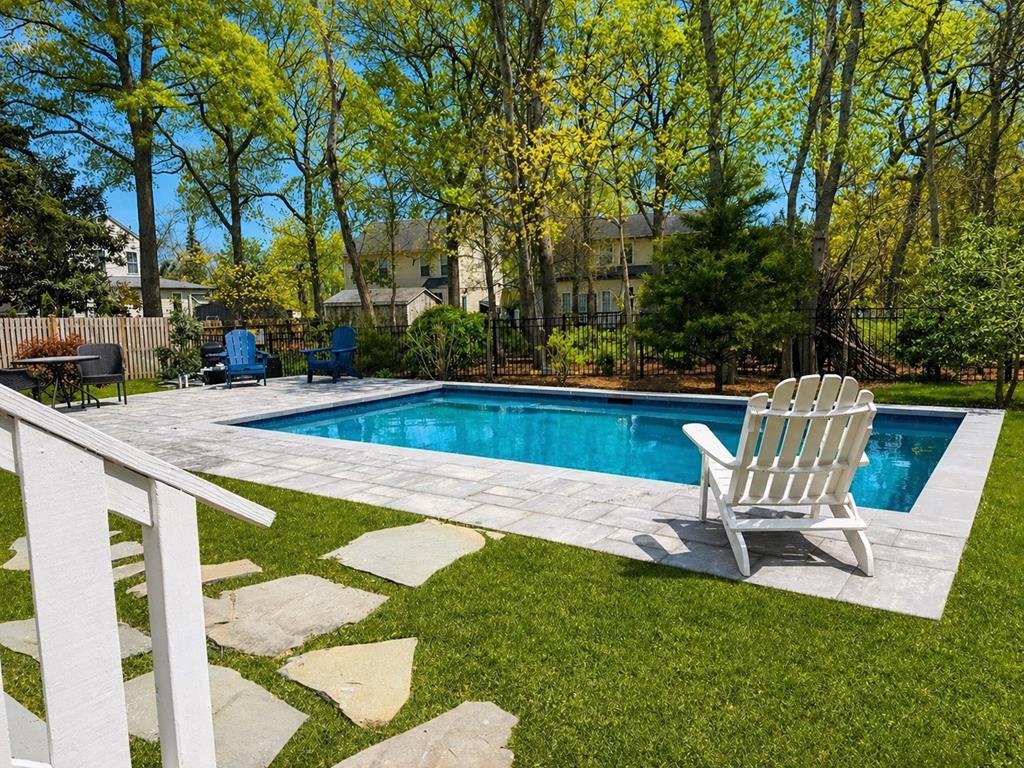 image Private heated pool with stone patio and tree-lined backyard — your outdoor escape after a day at the Cape May beaches