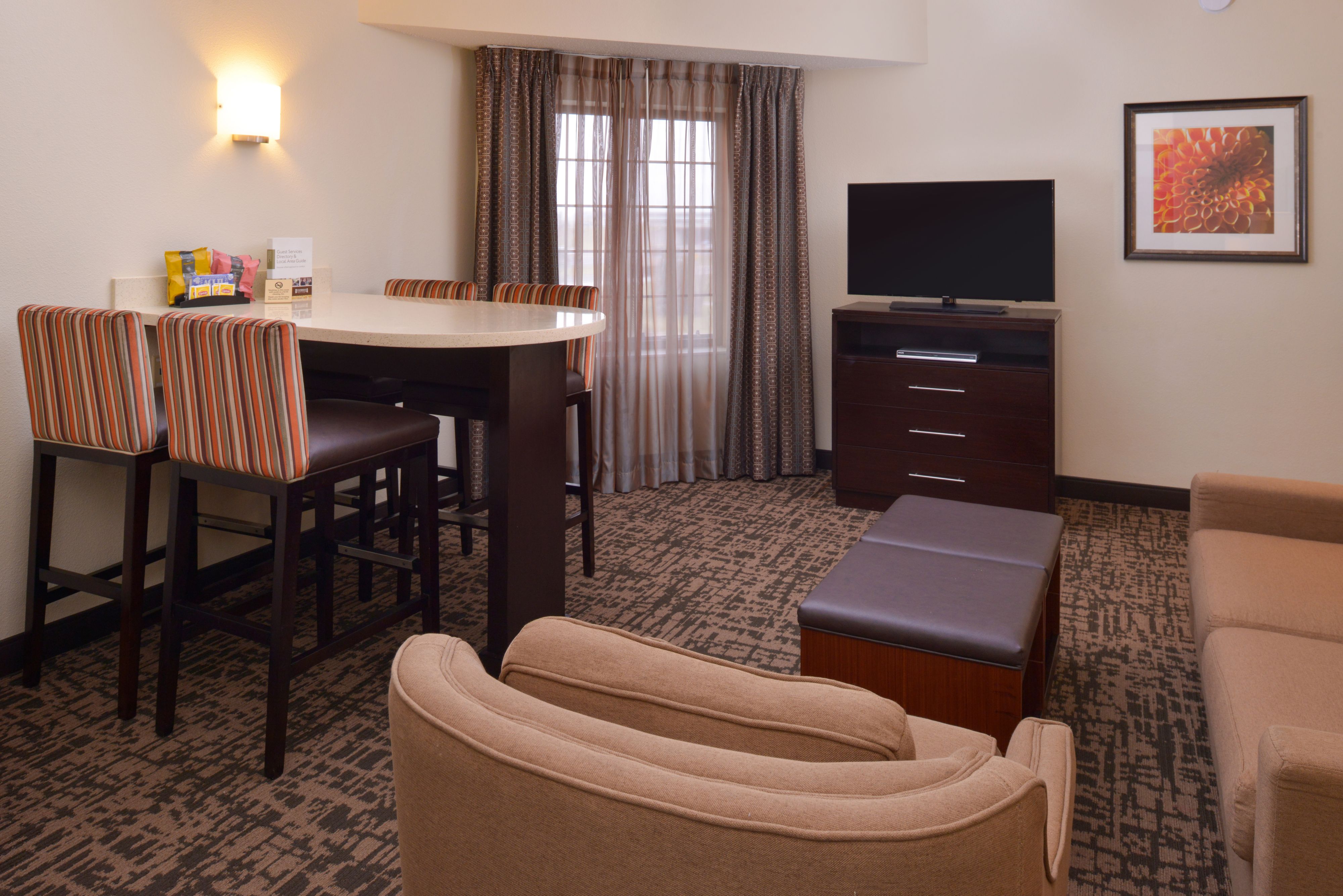 image Open living and dining area with flat-screen TV and seating.