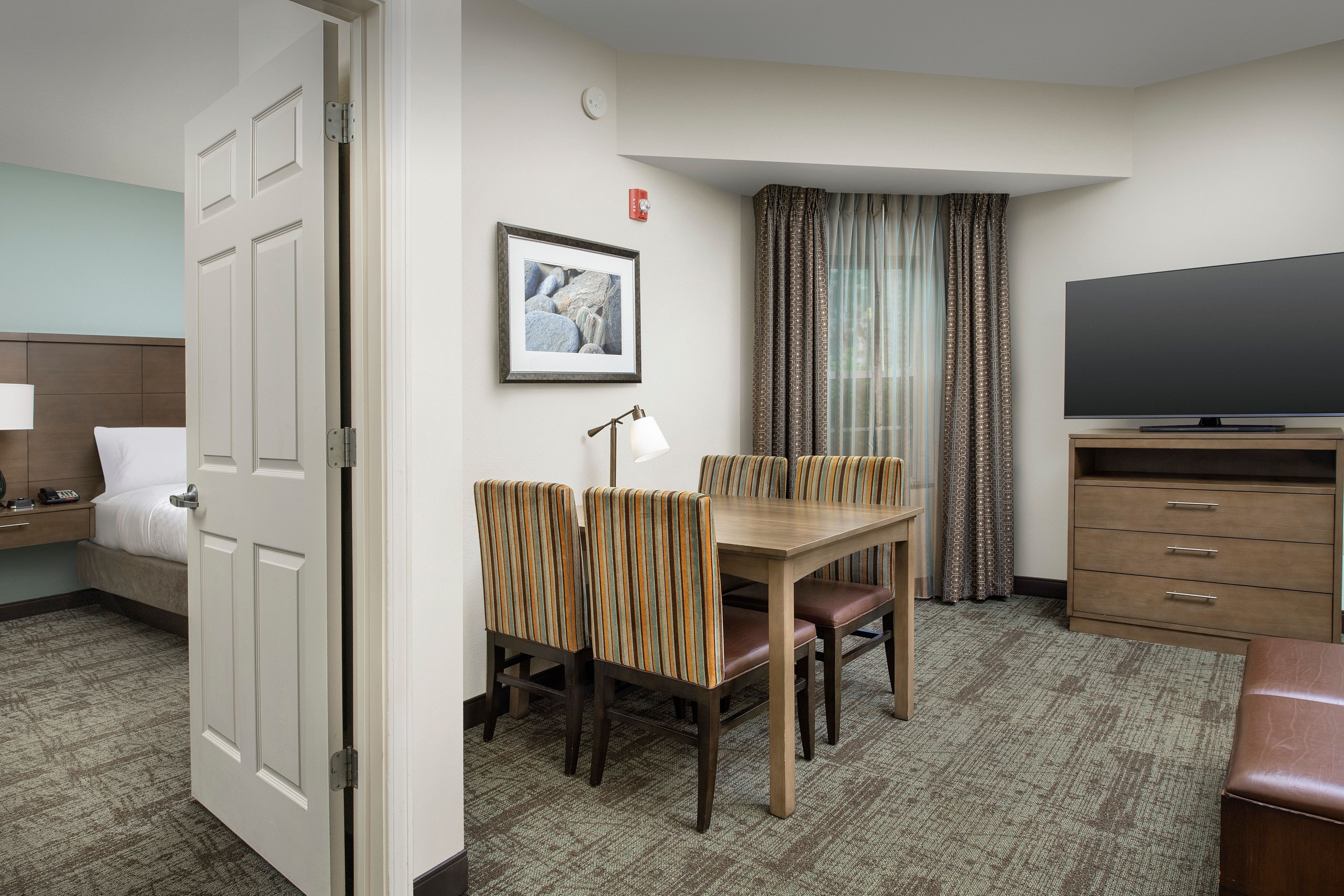 image Dining and seating area with TV, table, and striped armchairs.