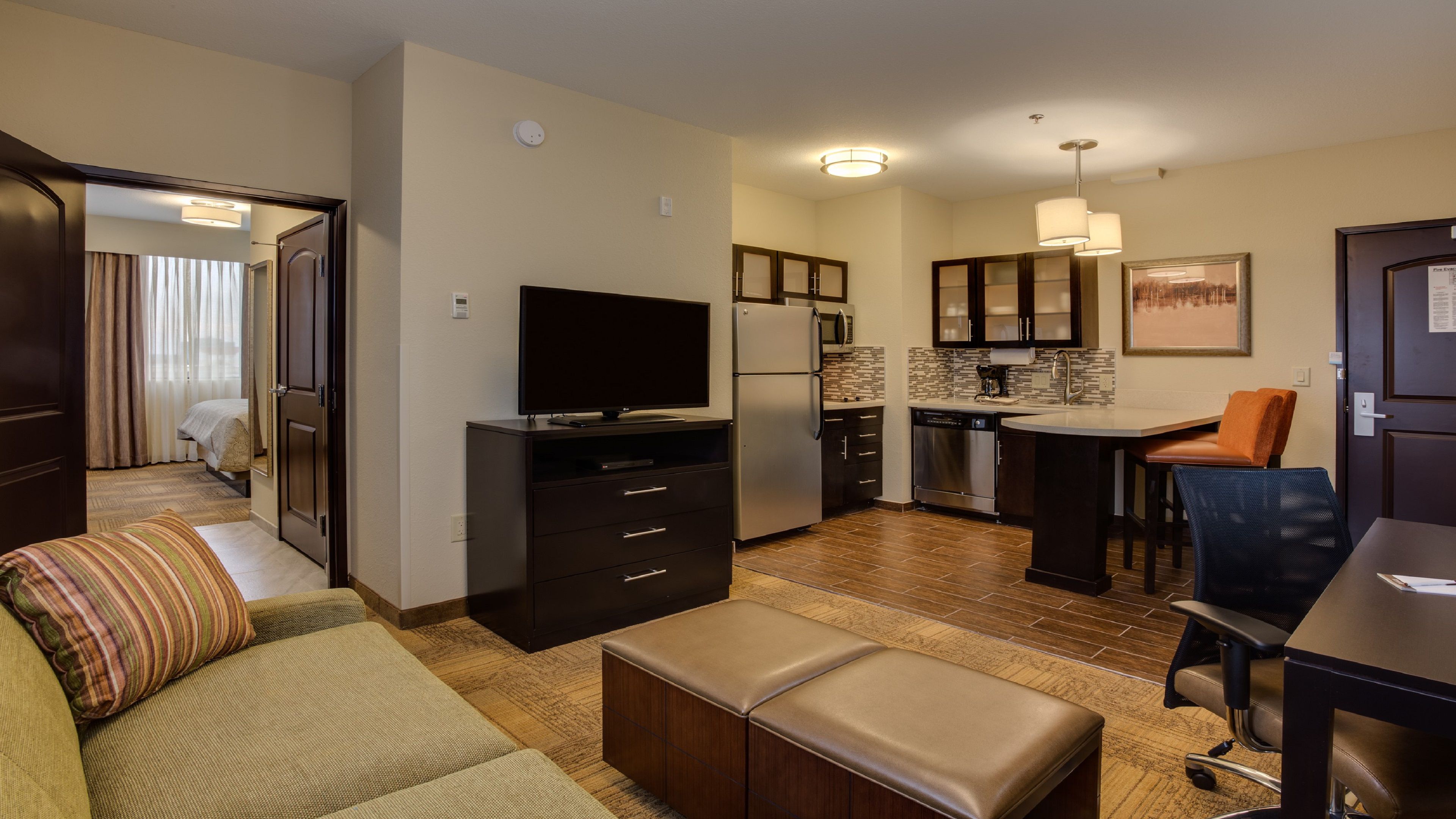 image Open-plan living area and fully equipped kitchenette with refrigerator, sofa, and flat-screen TV.