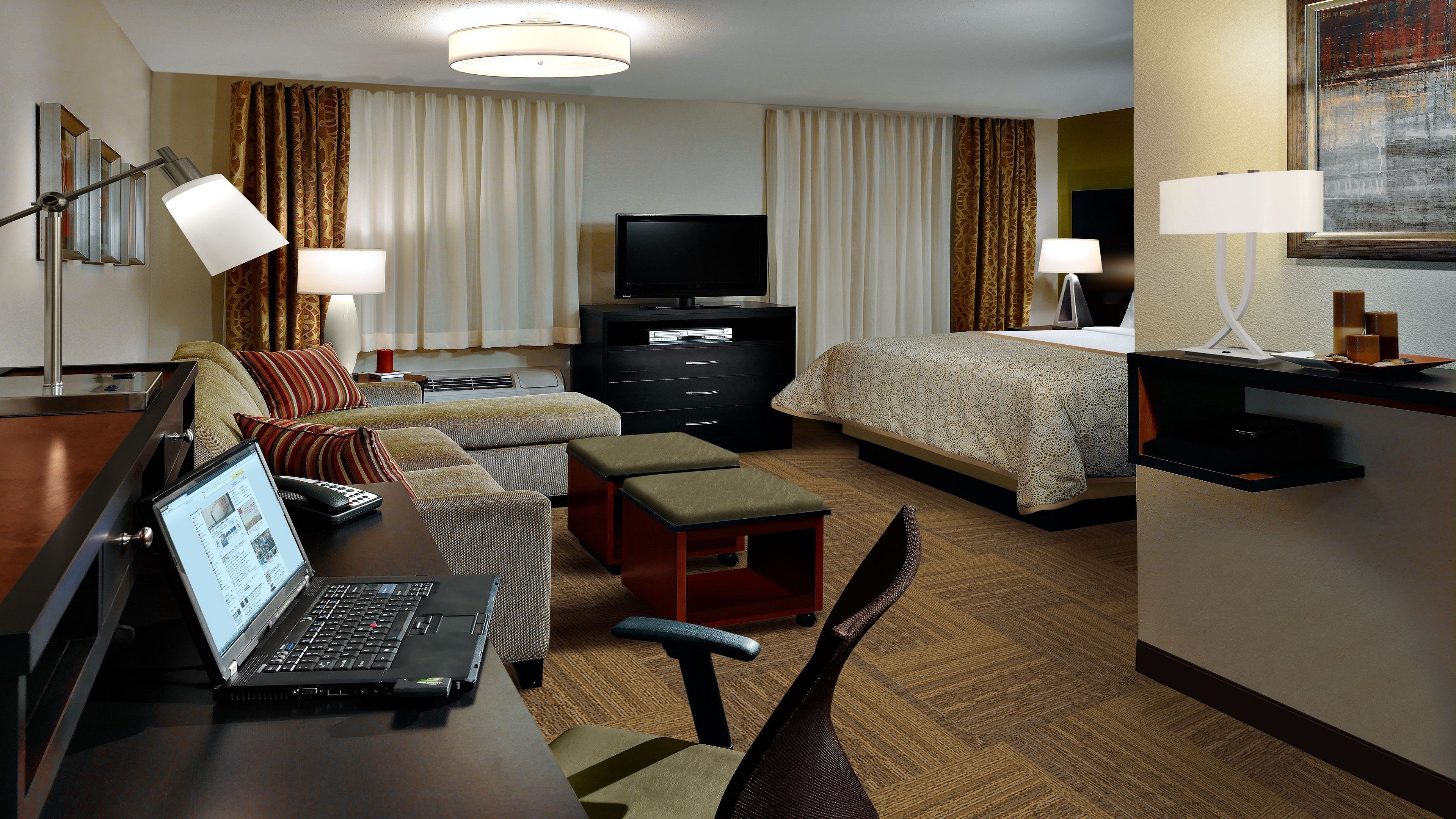 image Bright living area with sofa, dedicated work desk, and bedroom visible in the background.