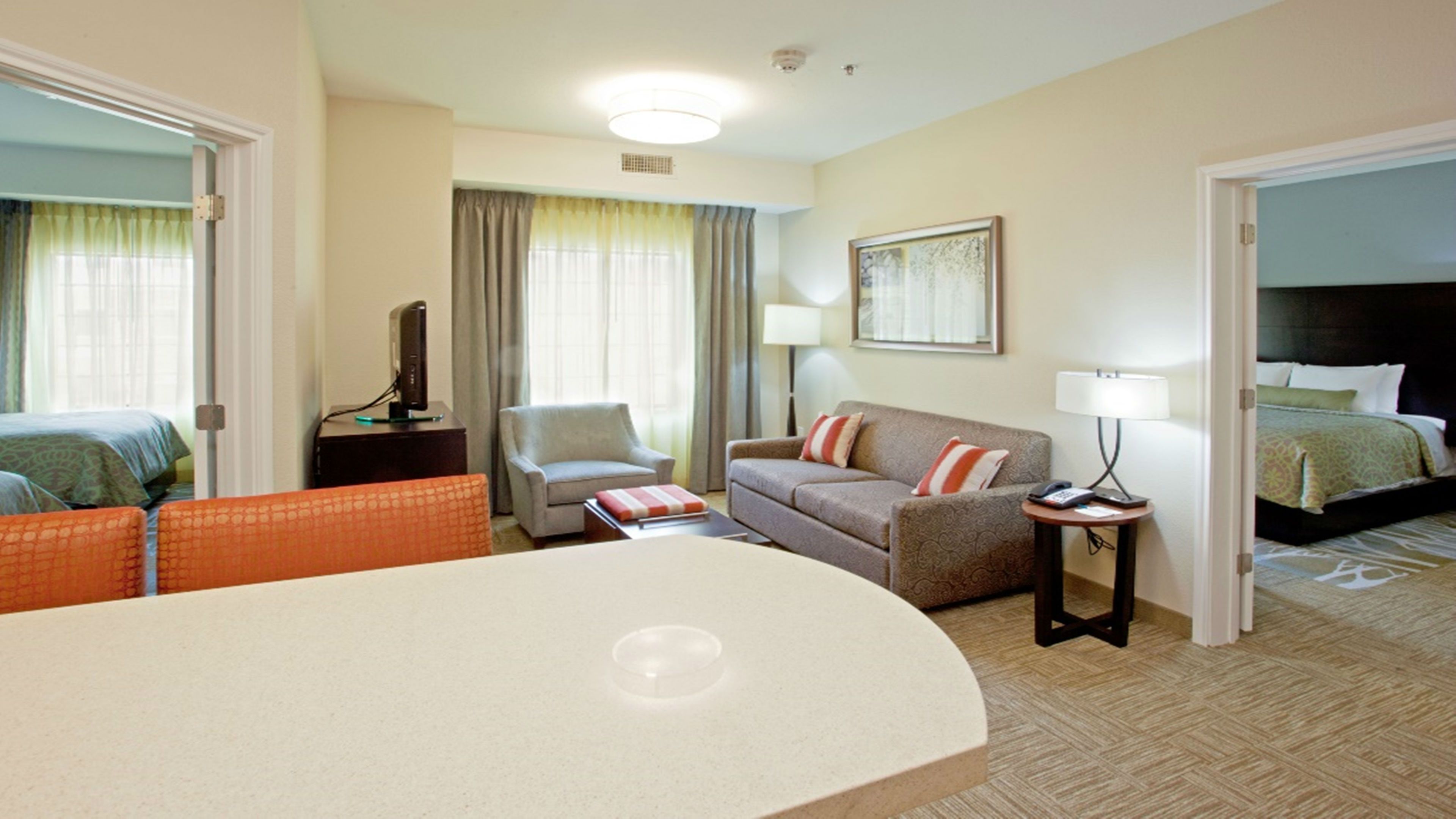 image Open living area with sofa, armchair, TV, and kitchen bar.