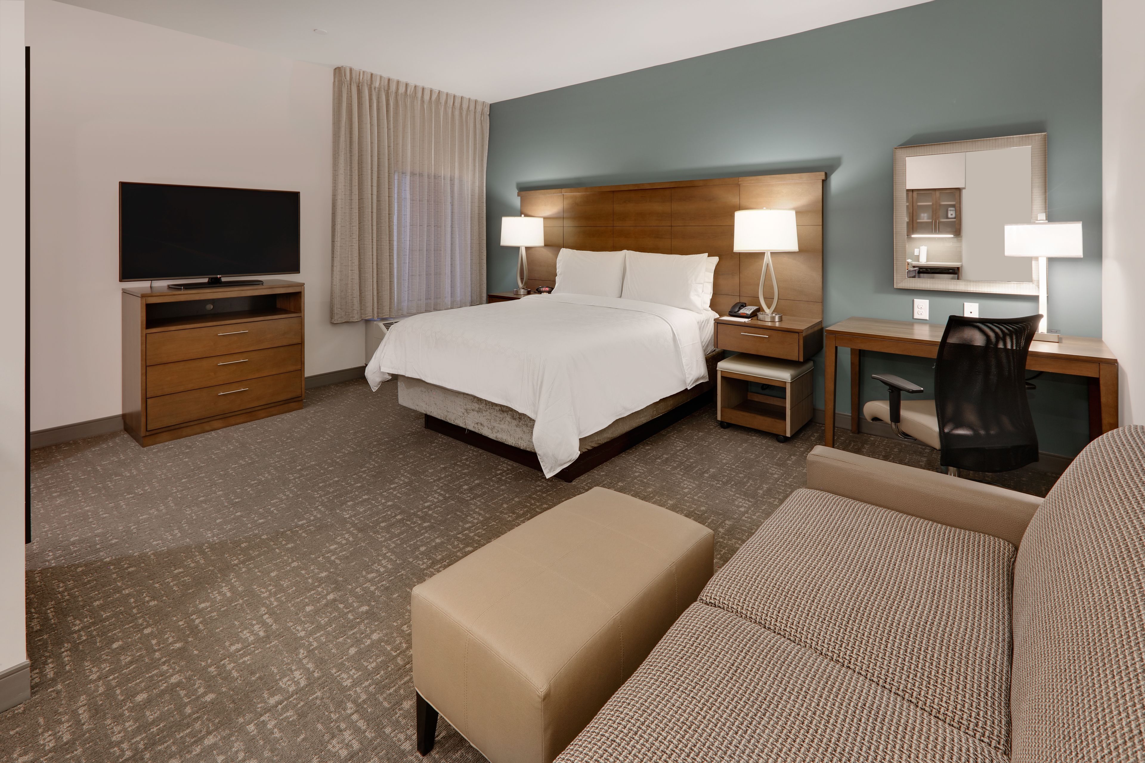image Bright and airy studio bedroom with elegant queen bed and furnishings.