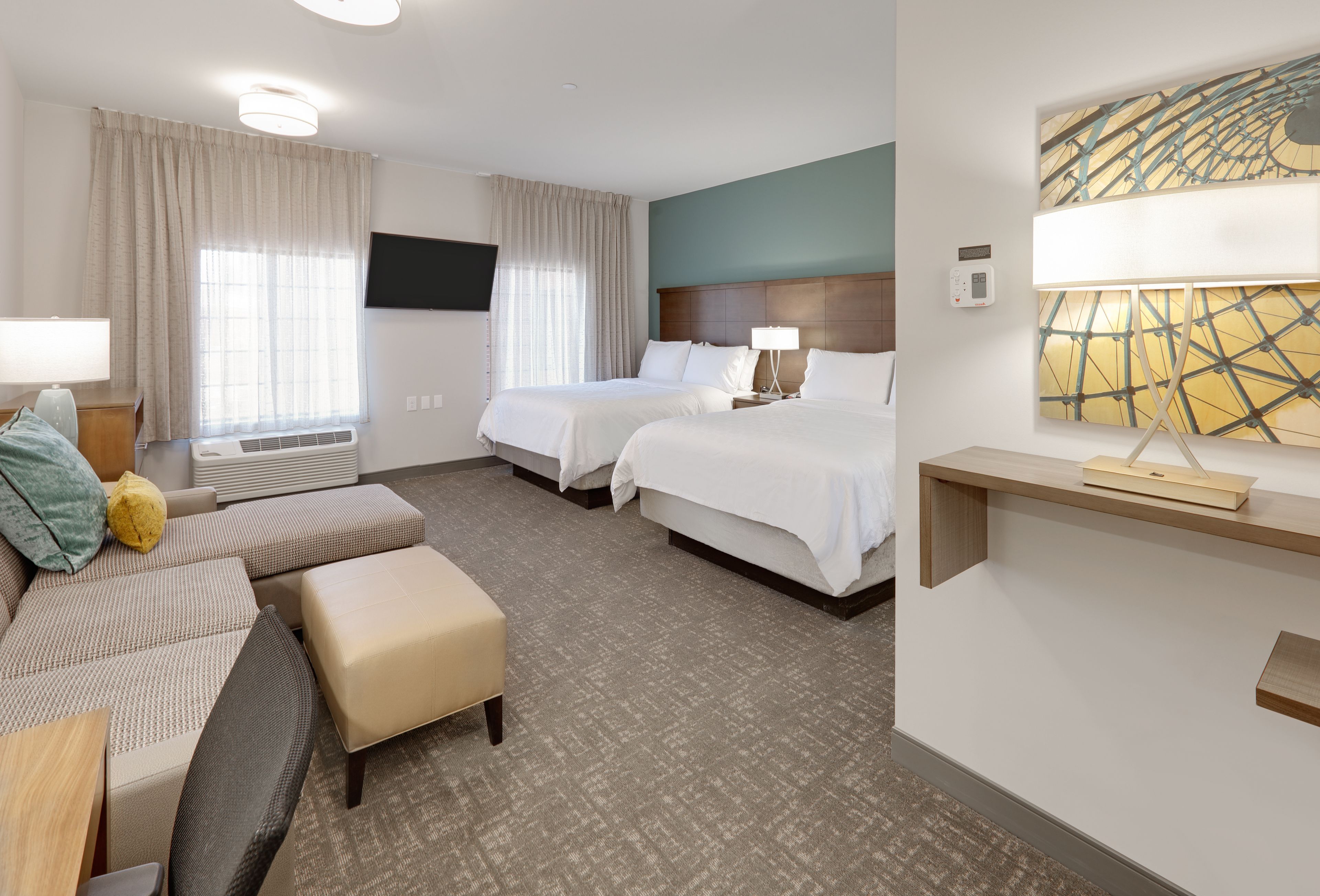image Bright studio suite featuring two comfortable queen beds and relaxing seating.