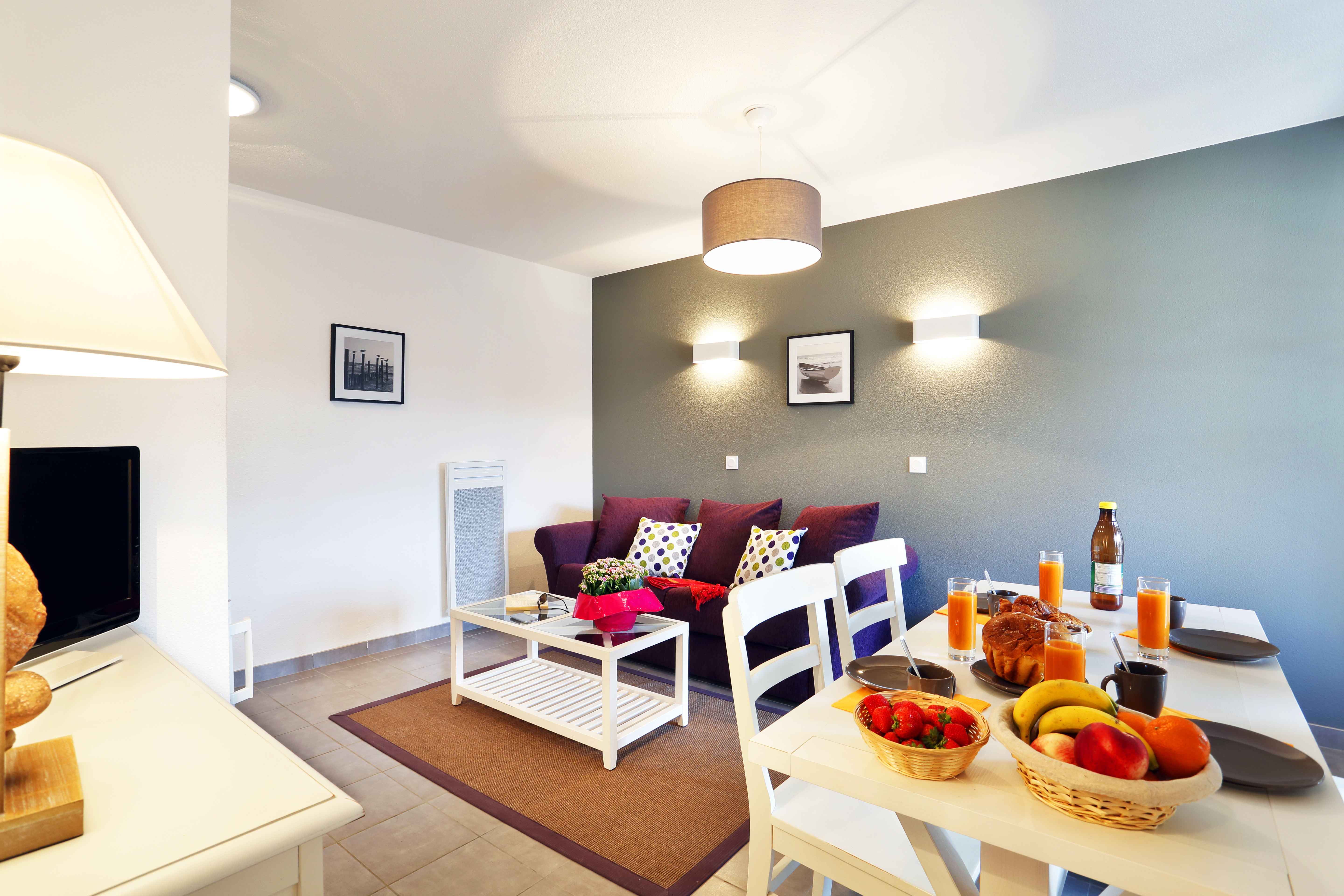image Bright living area with colourful cushions and natural light — TV and dining space share the open-plan ground floor.