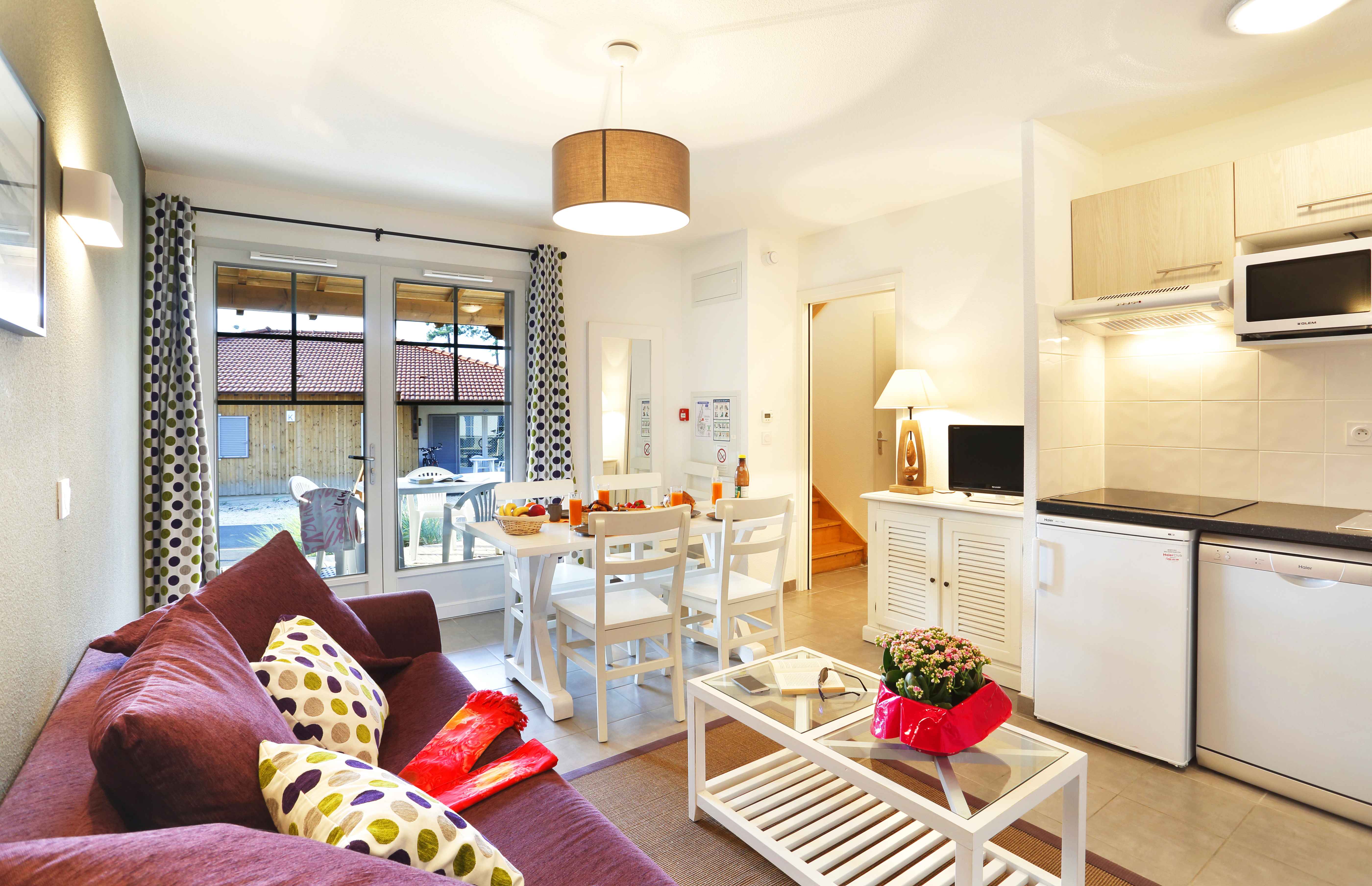 image Open-plan lounge with purple sofa and dining area — the sofa converts to a double bed for two additional guests.