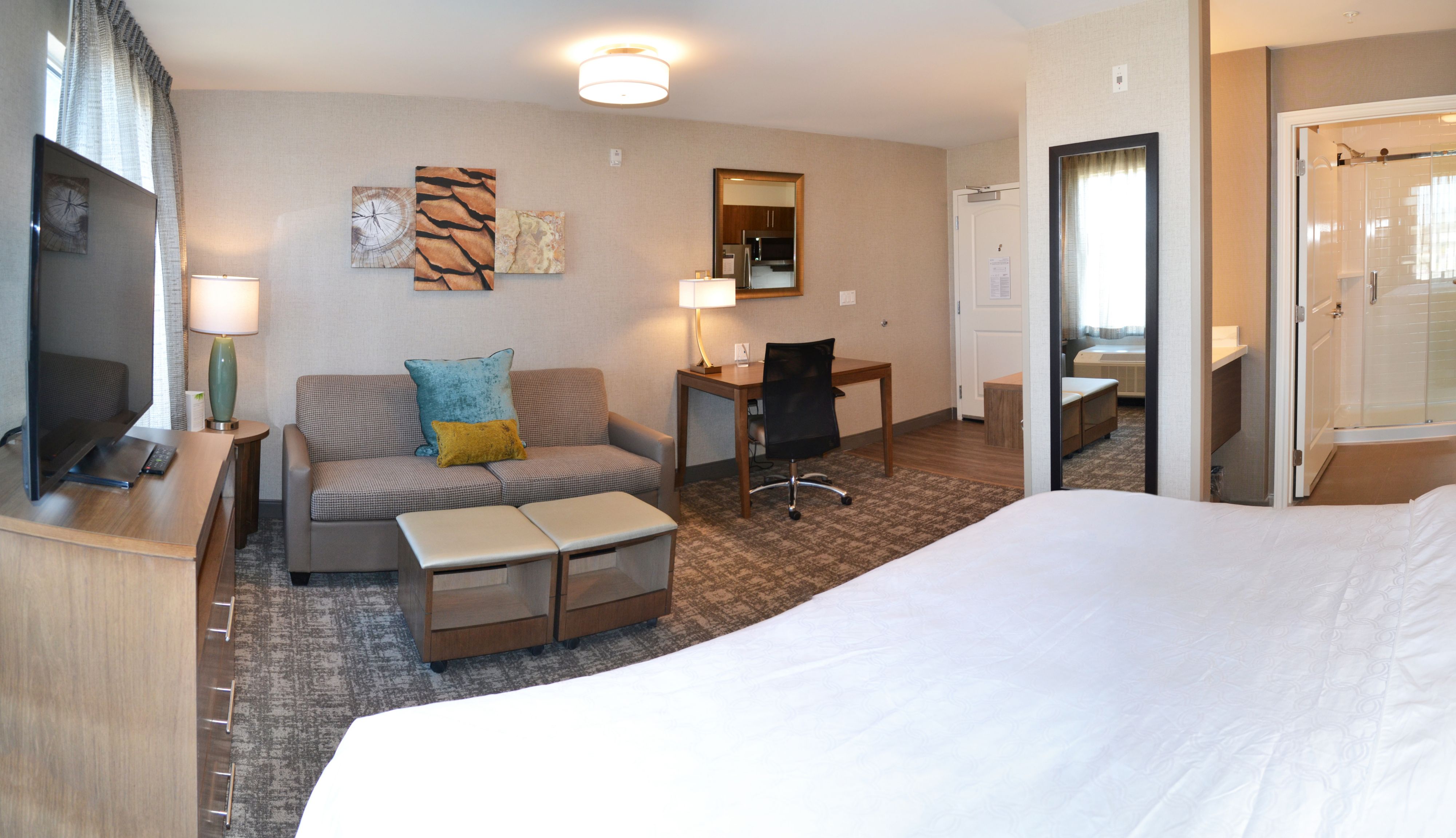image Spacious studio suite with modern decor and large flat-screen TV.