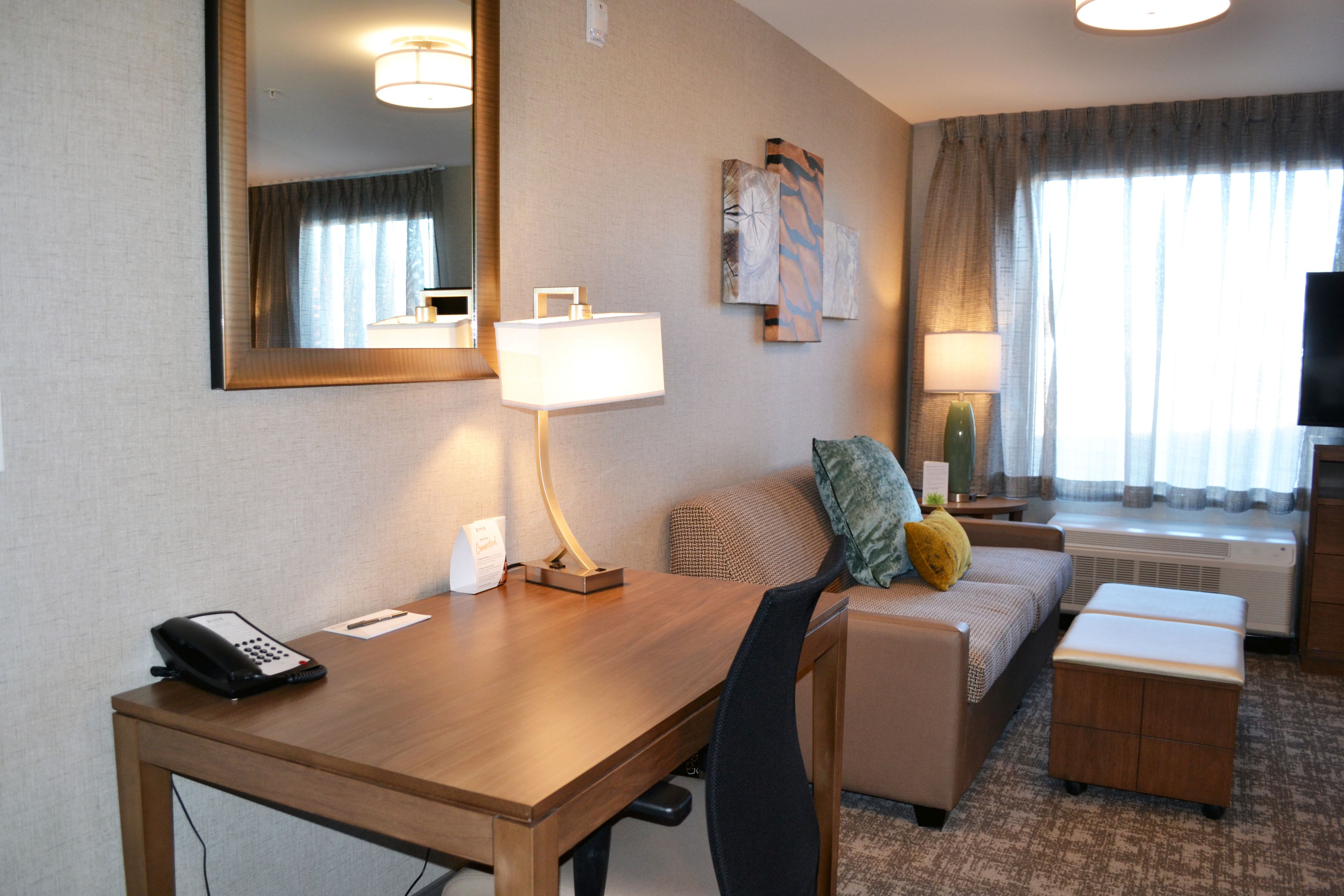 image Sitting area with sofa, desk, and lamp near window.