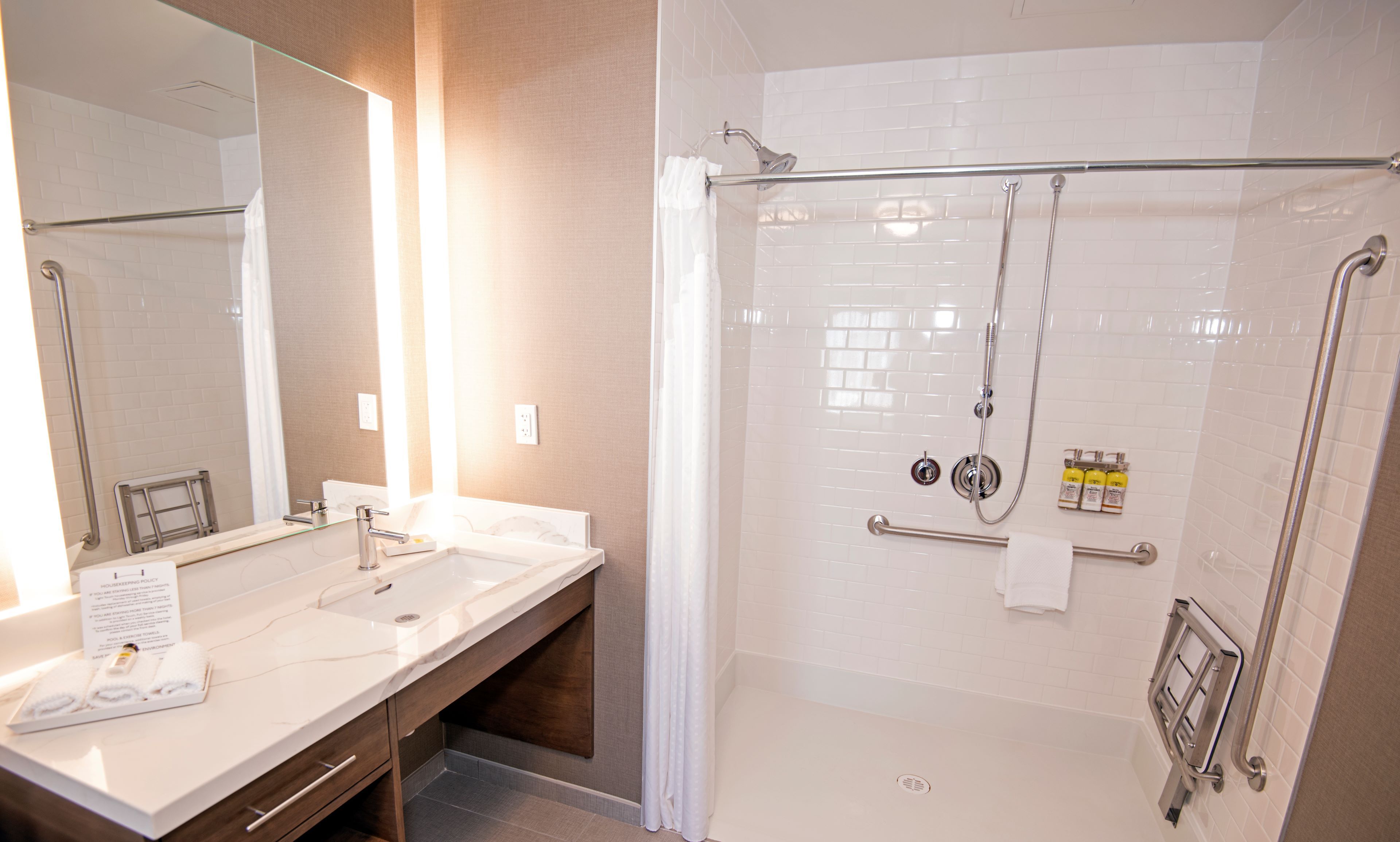 image Accessible bathroom featuring a roll-in shower and safety rails.