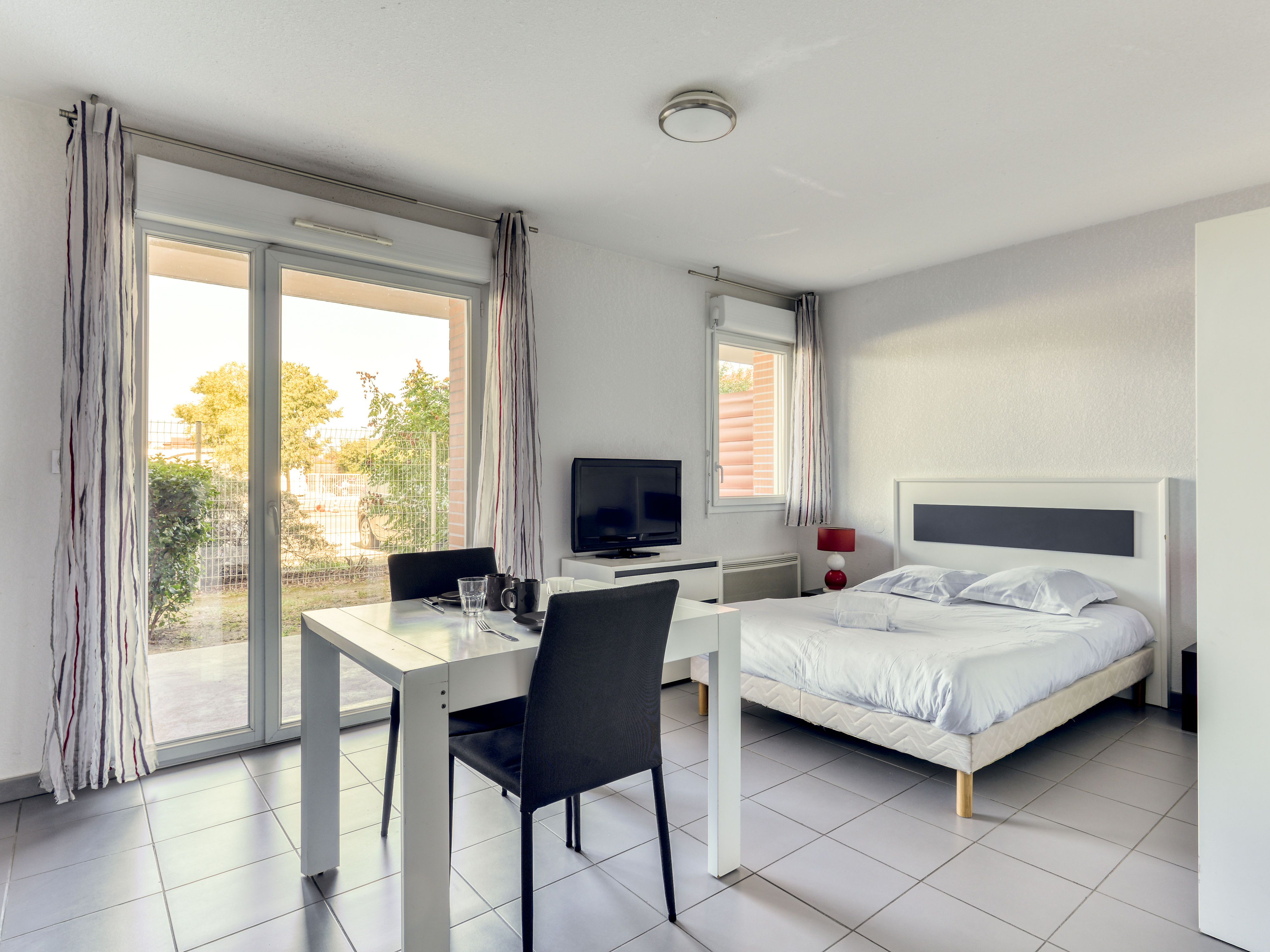 image Double bed, dining area, and flat-screen TV in an open layout with sliding doors to the terrace