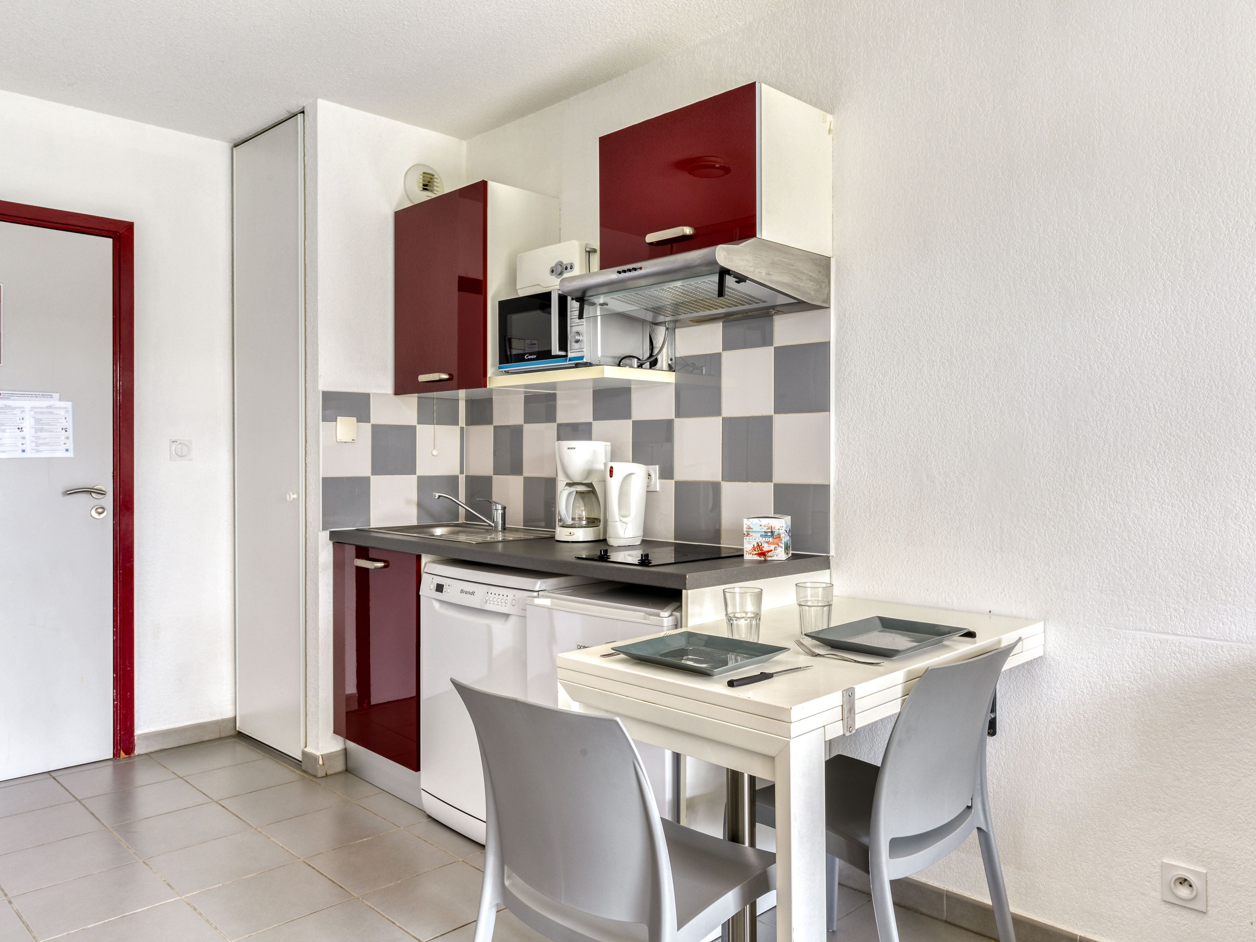 image Red kitchenette with ceramic hob, microwave, dishwasher, and coffee machine