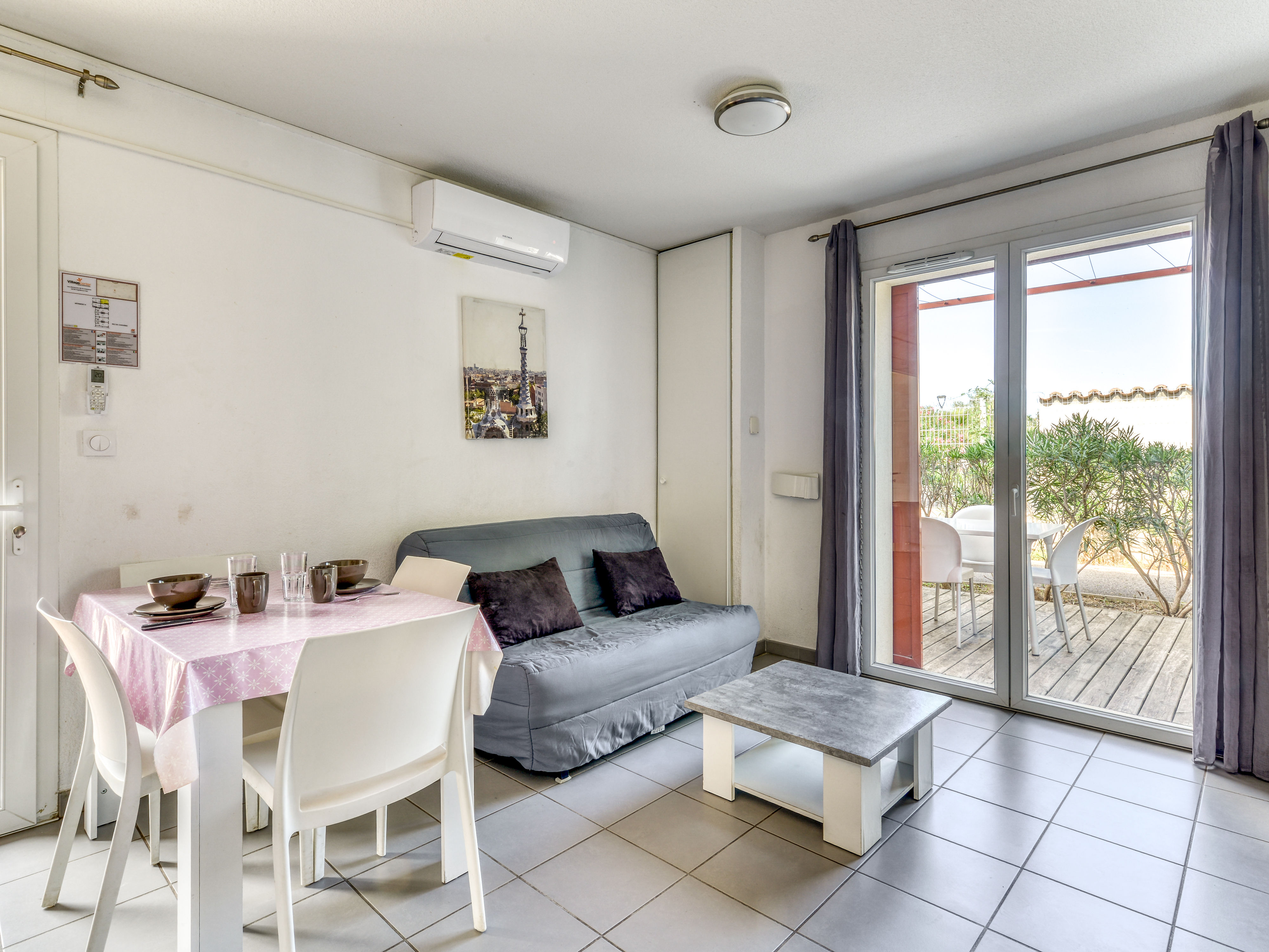 image Open-plan living area with sofa bed and flat-screen TV leads straight out to the furnished terrace