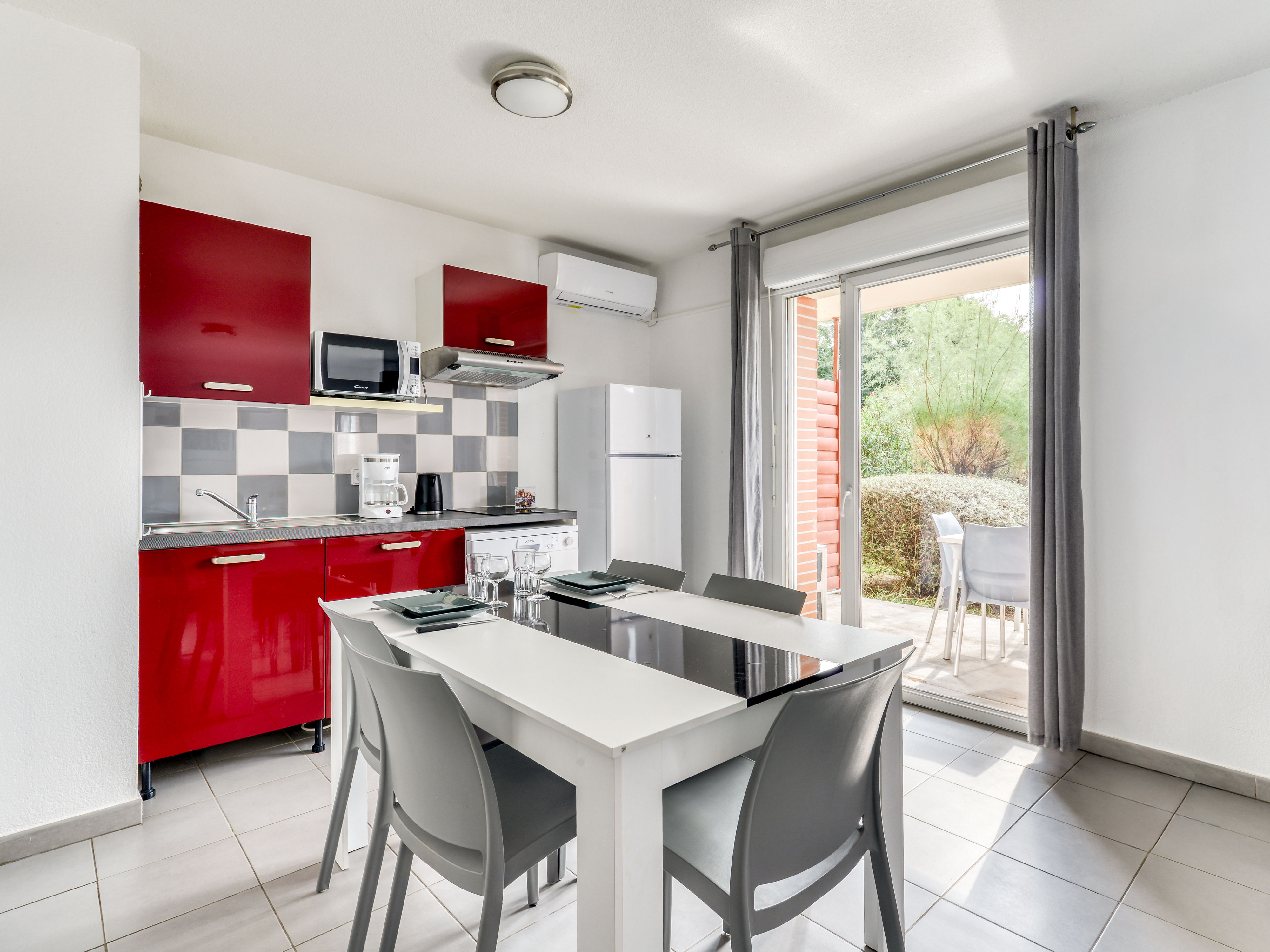image Red kitchenette with ceramic hob, microwave, and dishwasher — dining area right alongside