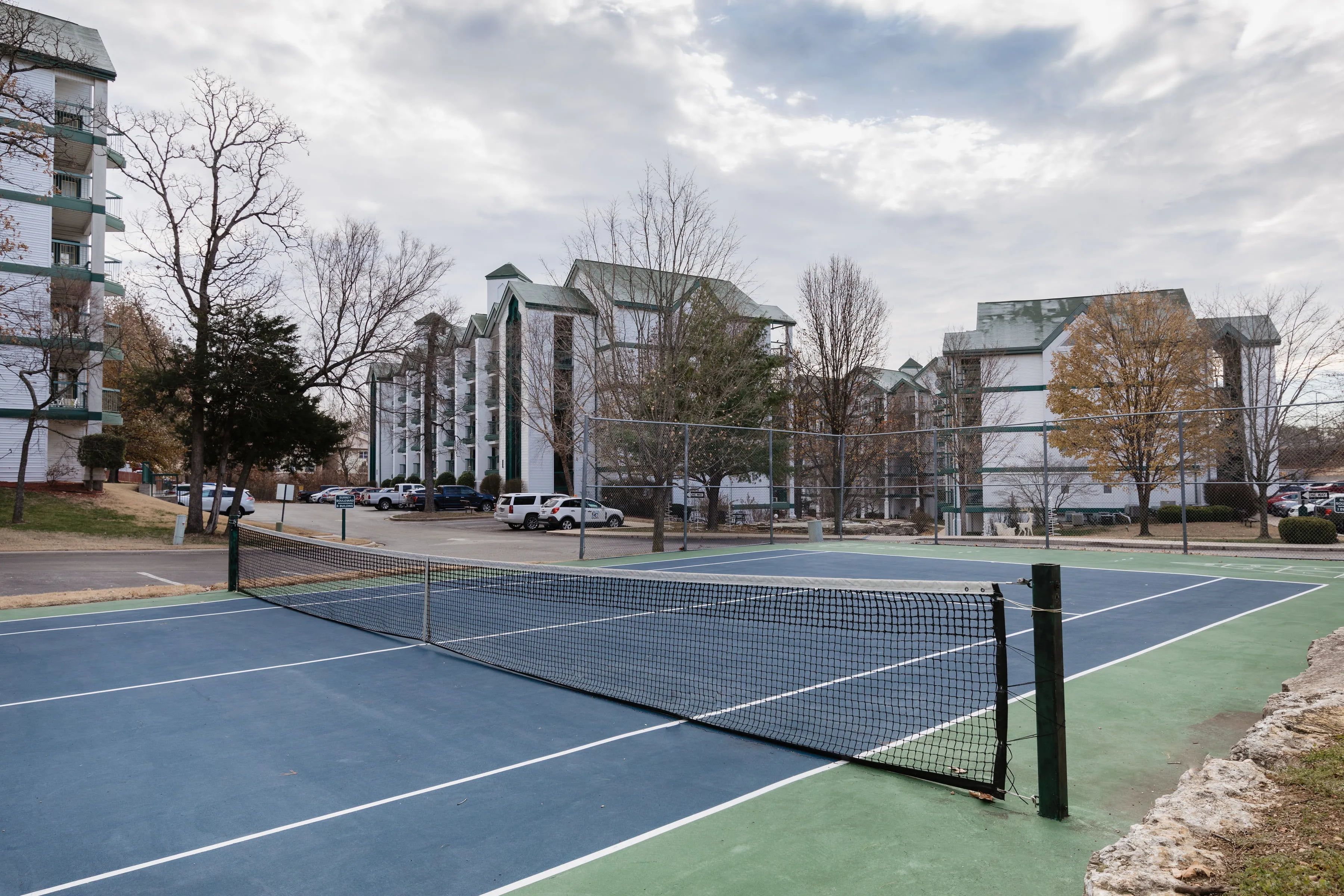 image Outdoor tennis court surrounded by resort buildings.