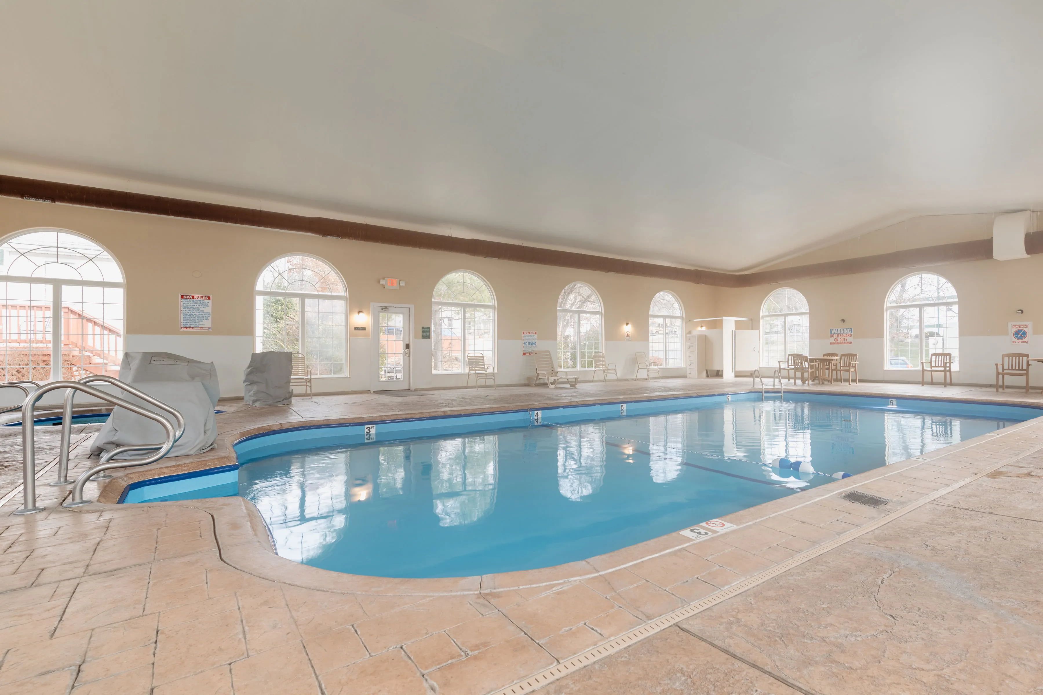 image Indoor pool with arched windows and spacious seating area.