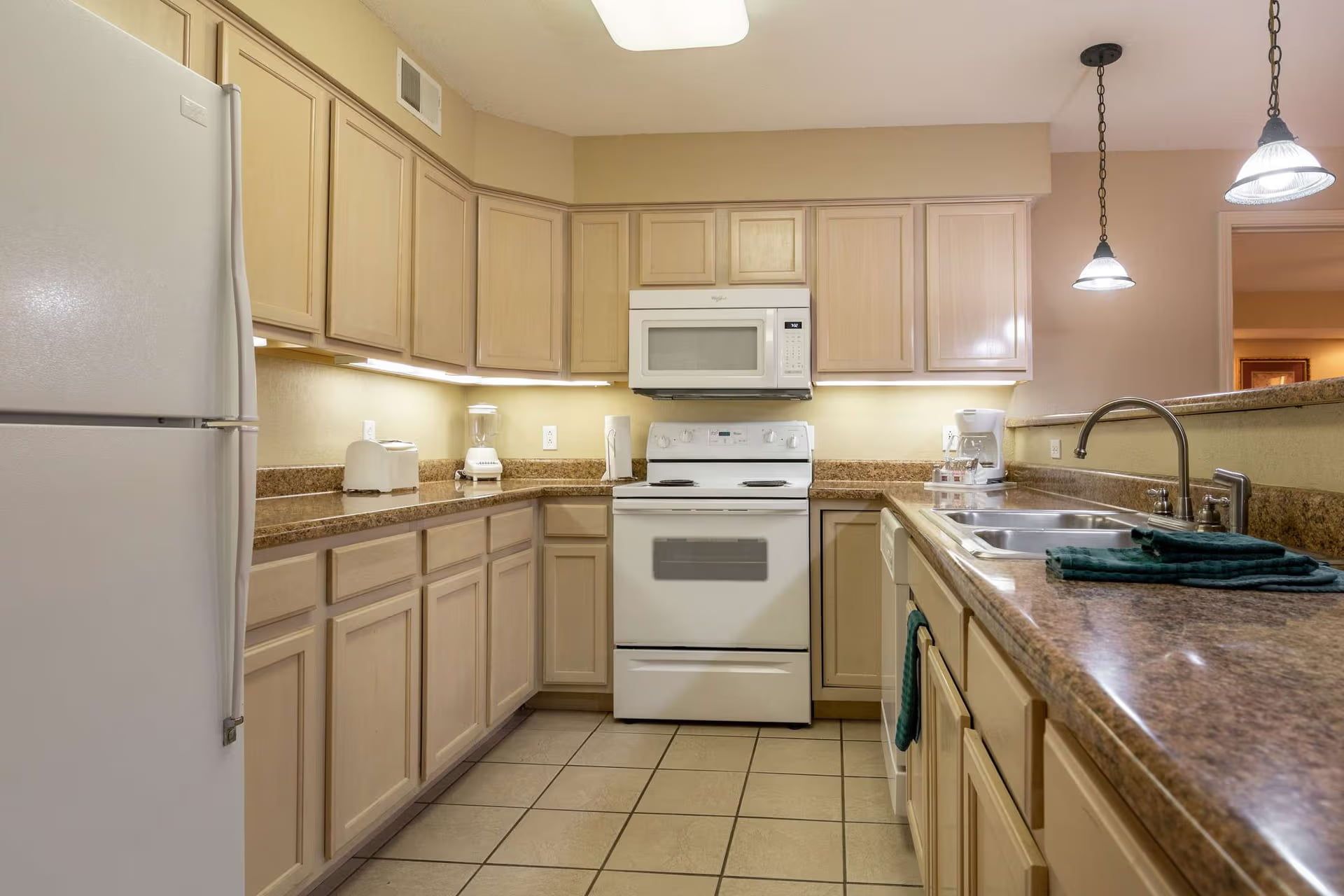 image Well-appointed kitchen with white appliances and tile flooring.
