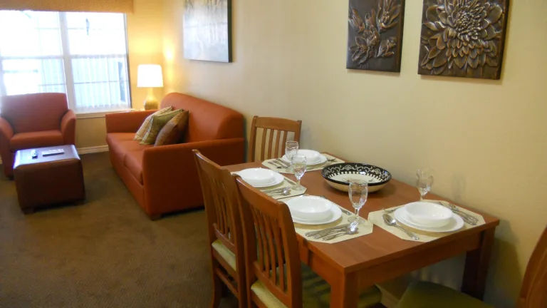 image Dining area with table set for four and orange chairs.