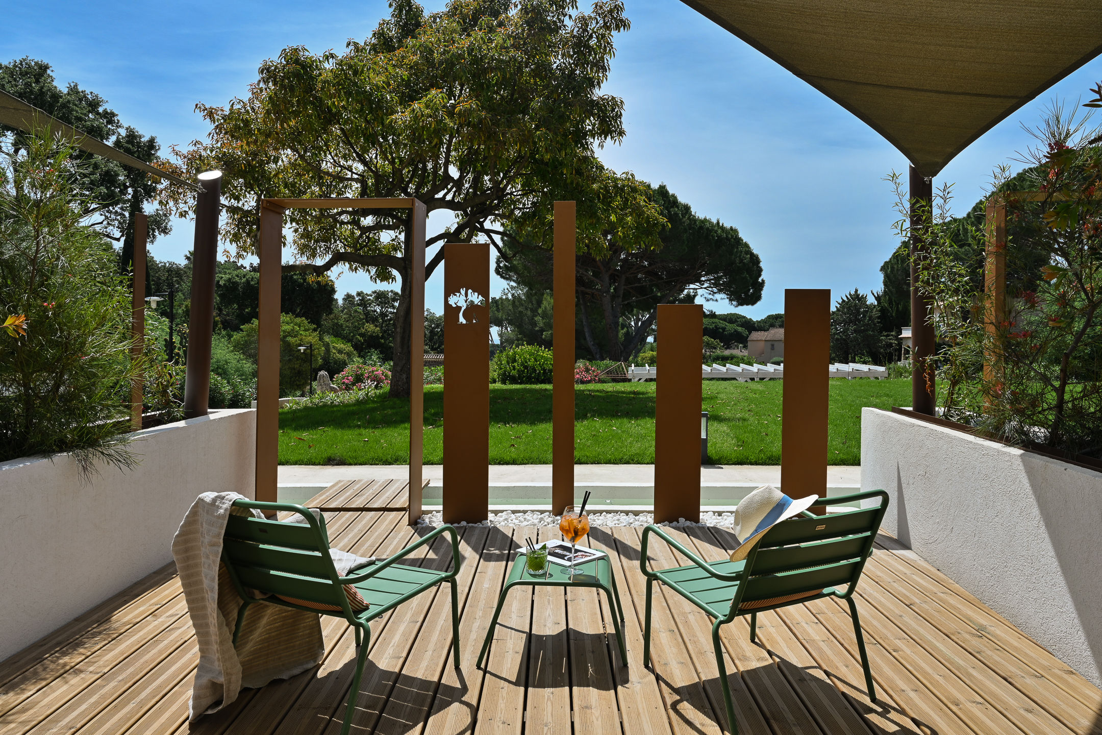 image Your private shaded terrace — two green chairs, a small table, and garden greenery on all sides