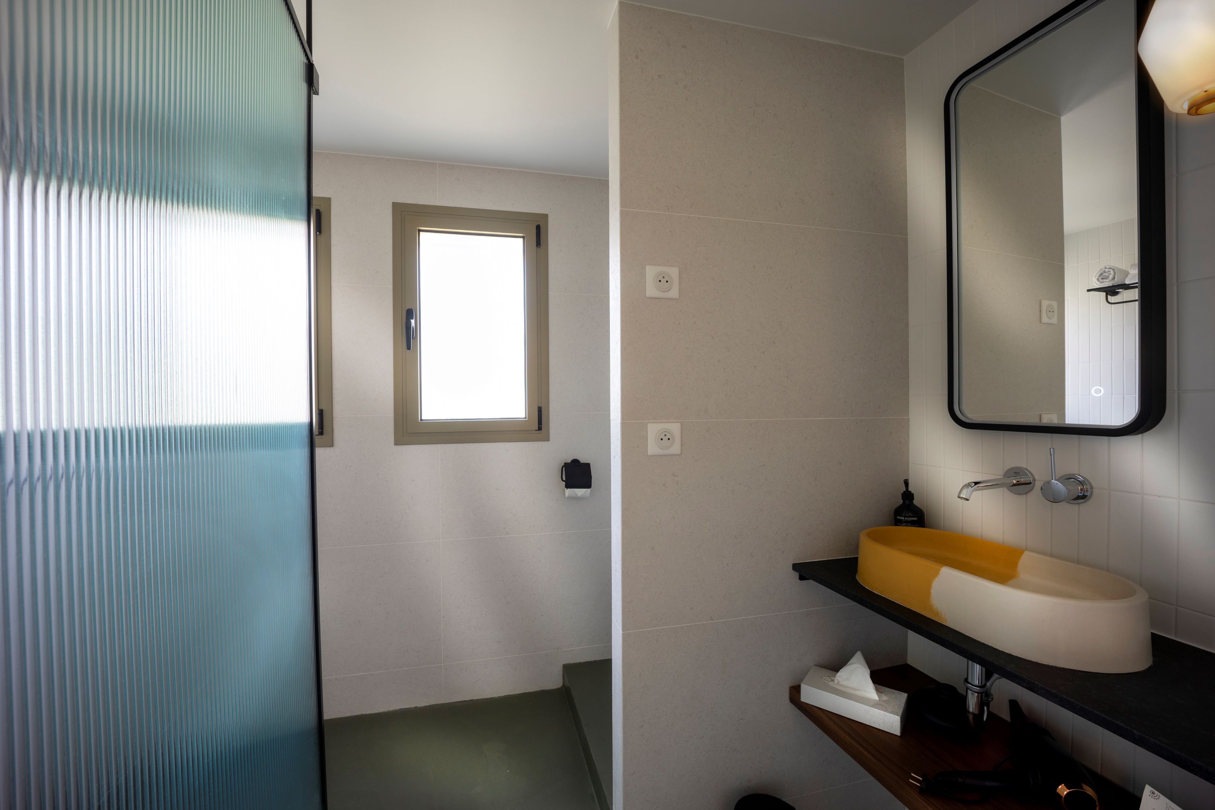 image Glass shower and an orange round sink on a dark countertop in the en-suite bathroom