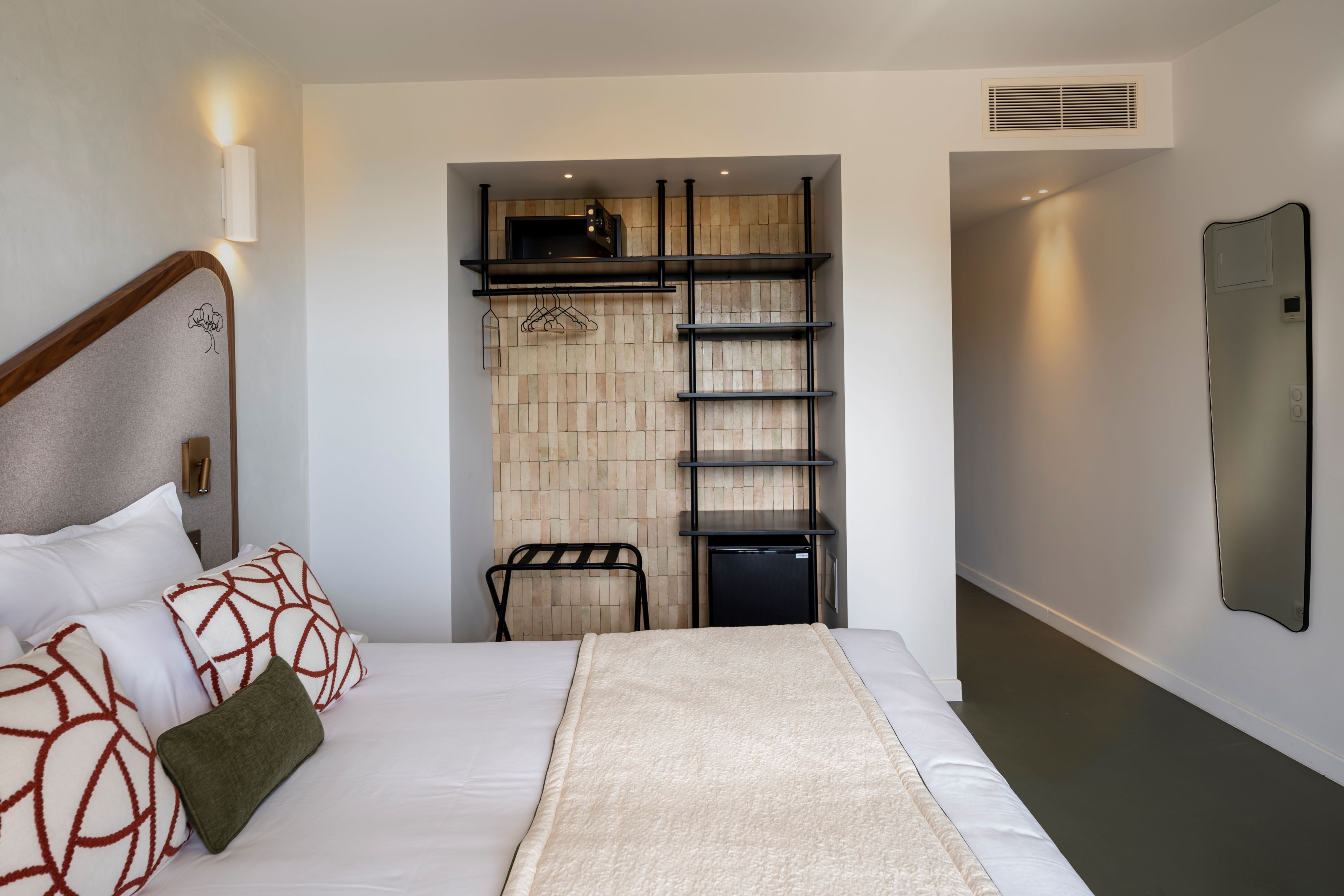 image Queen-made bed with white bedding, open shelving, and the in-room minibar fridge in the alcove