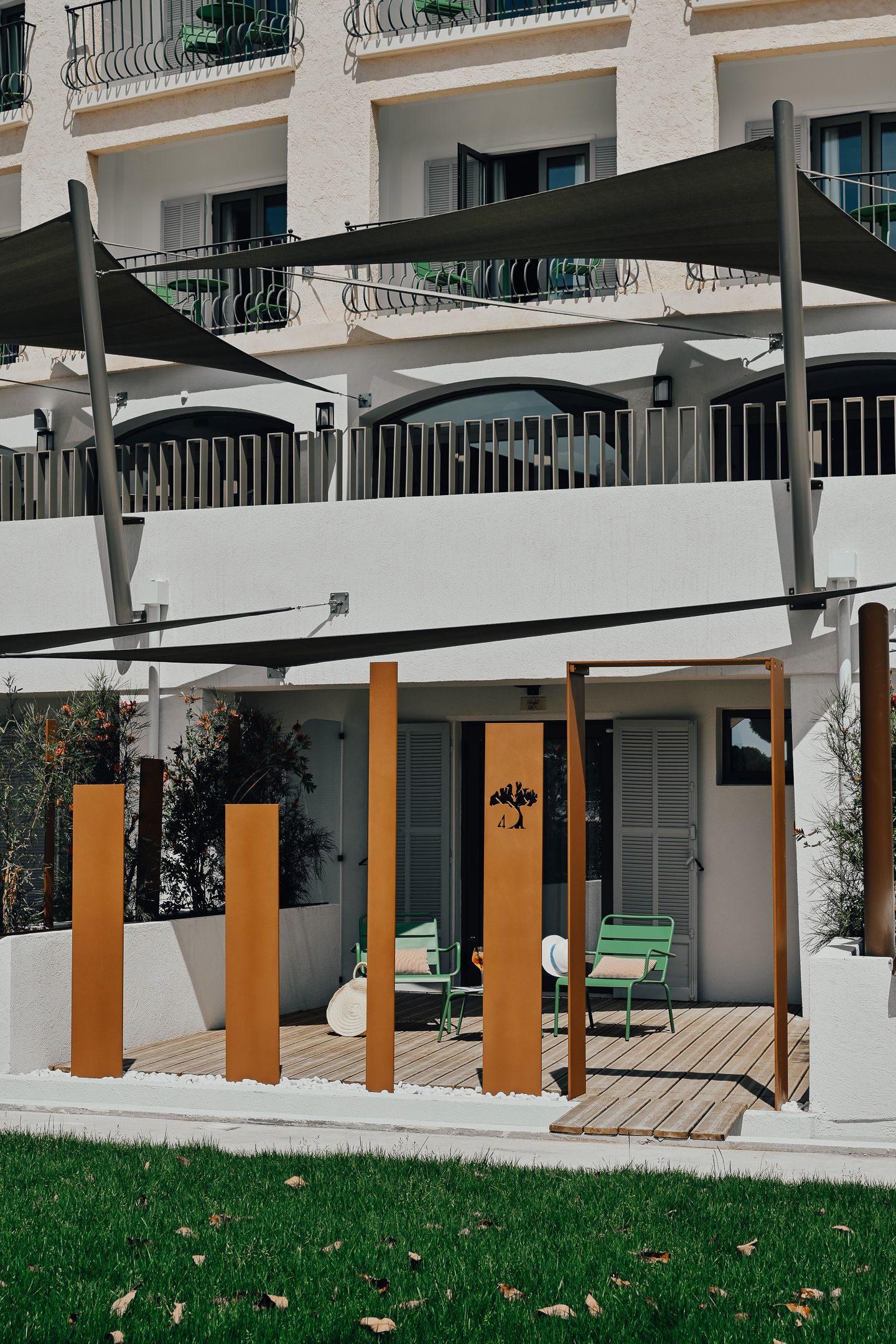 image The terrace enclosed by vertical metal panels — green seating and open lawn just beyond