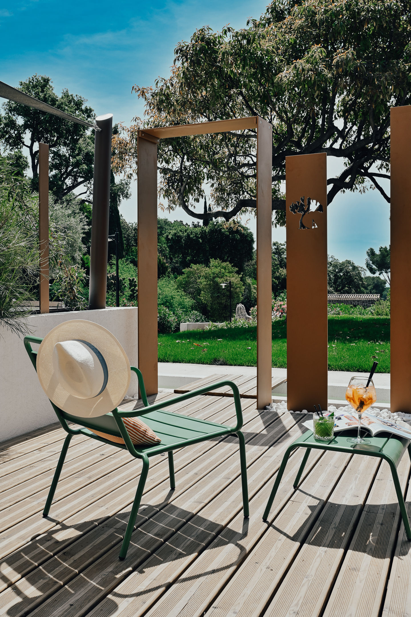 image Green metal chairs and a small table on the private shaded terrace, surrounded by garden trees