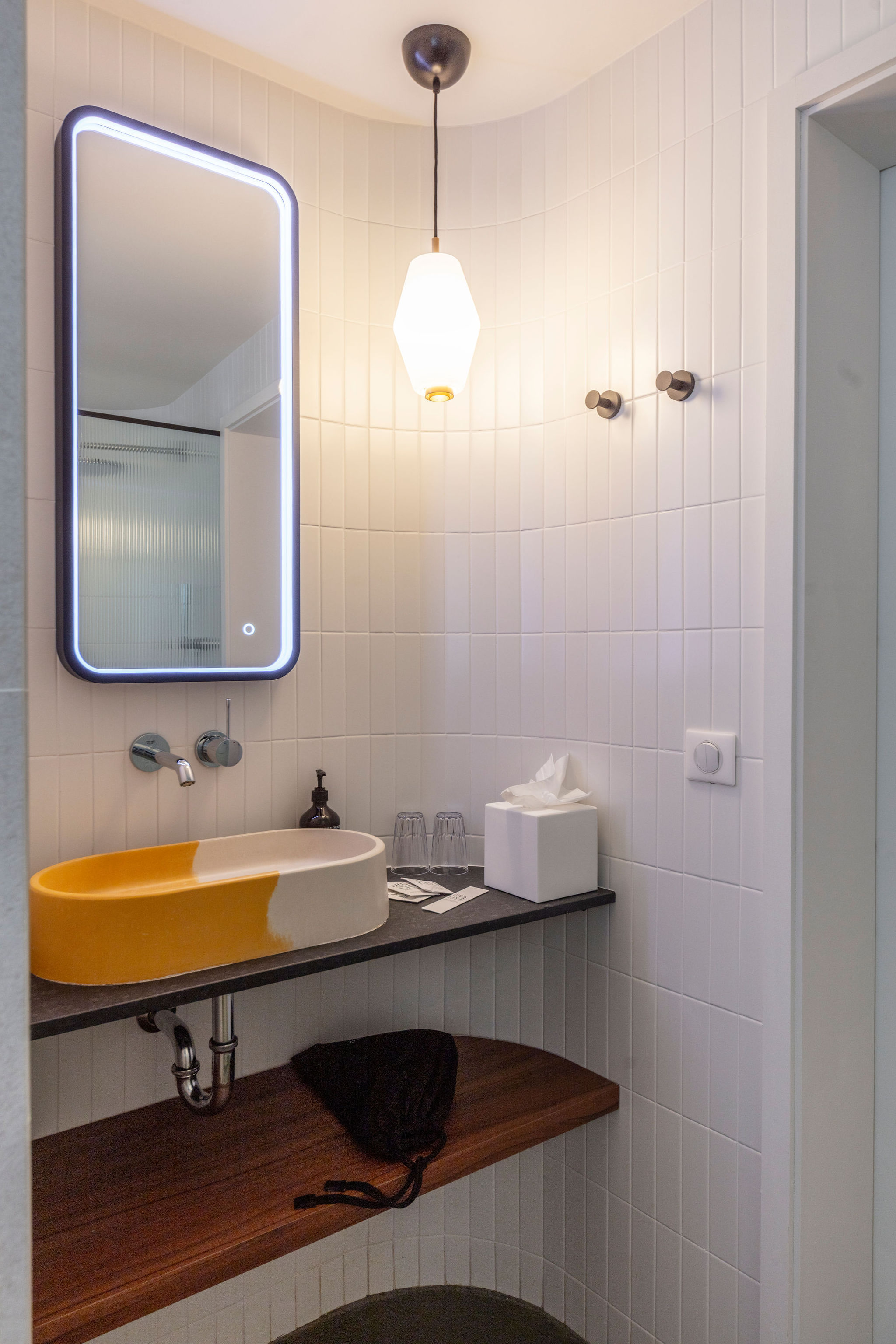 image Oval sink on a dark countertop with a round mirror and modern wall lighting in the en-suite