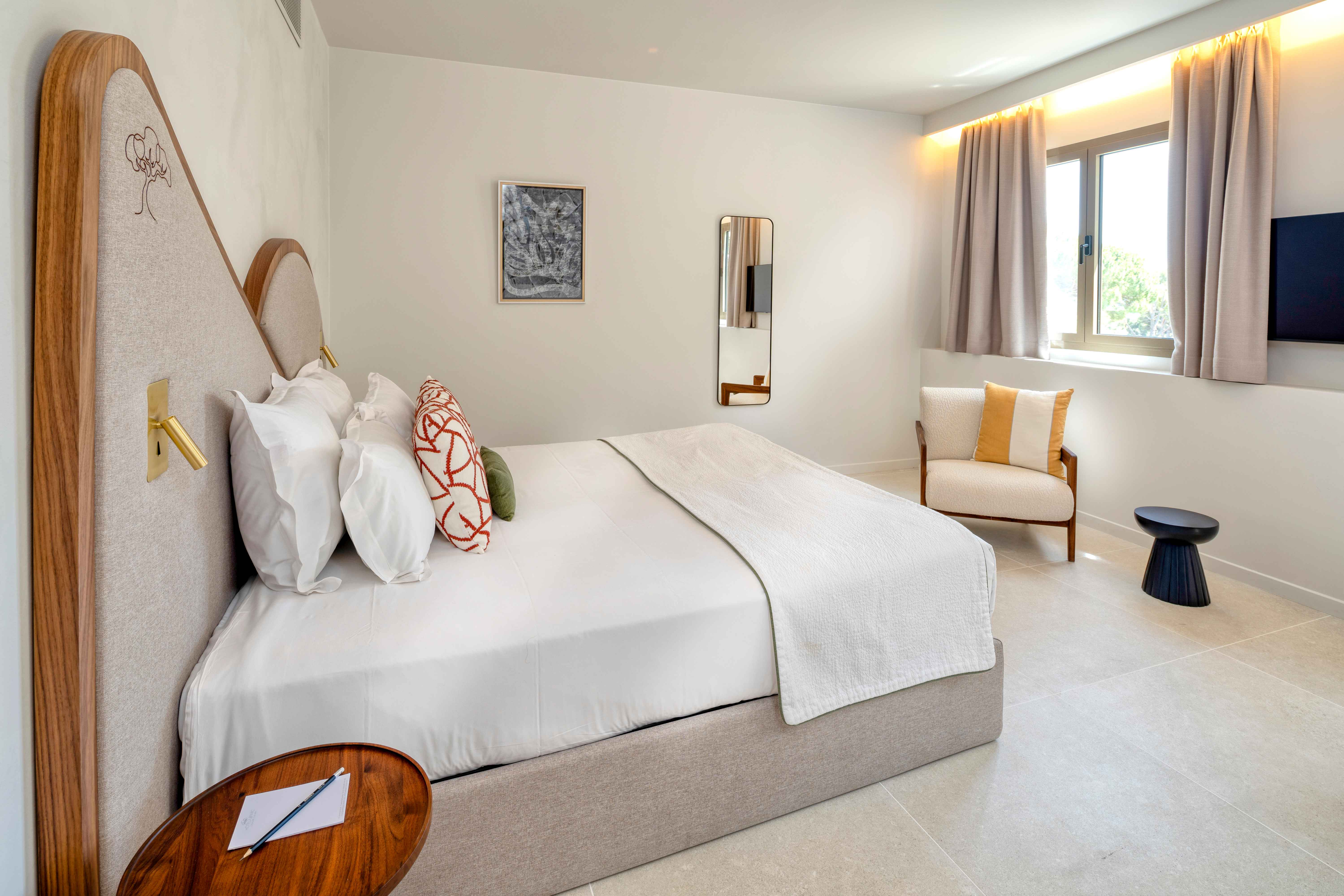 image Upper-level bedroom with wooden accent walls, a queen bed, and large windows overlooking the gardens