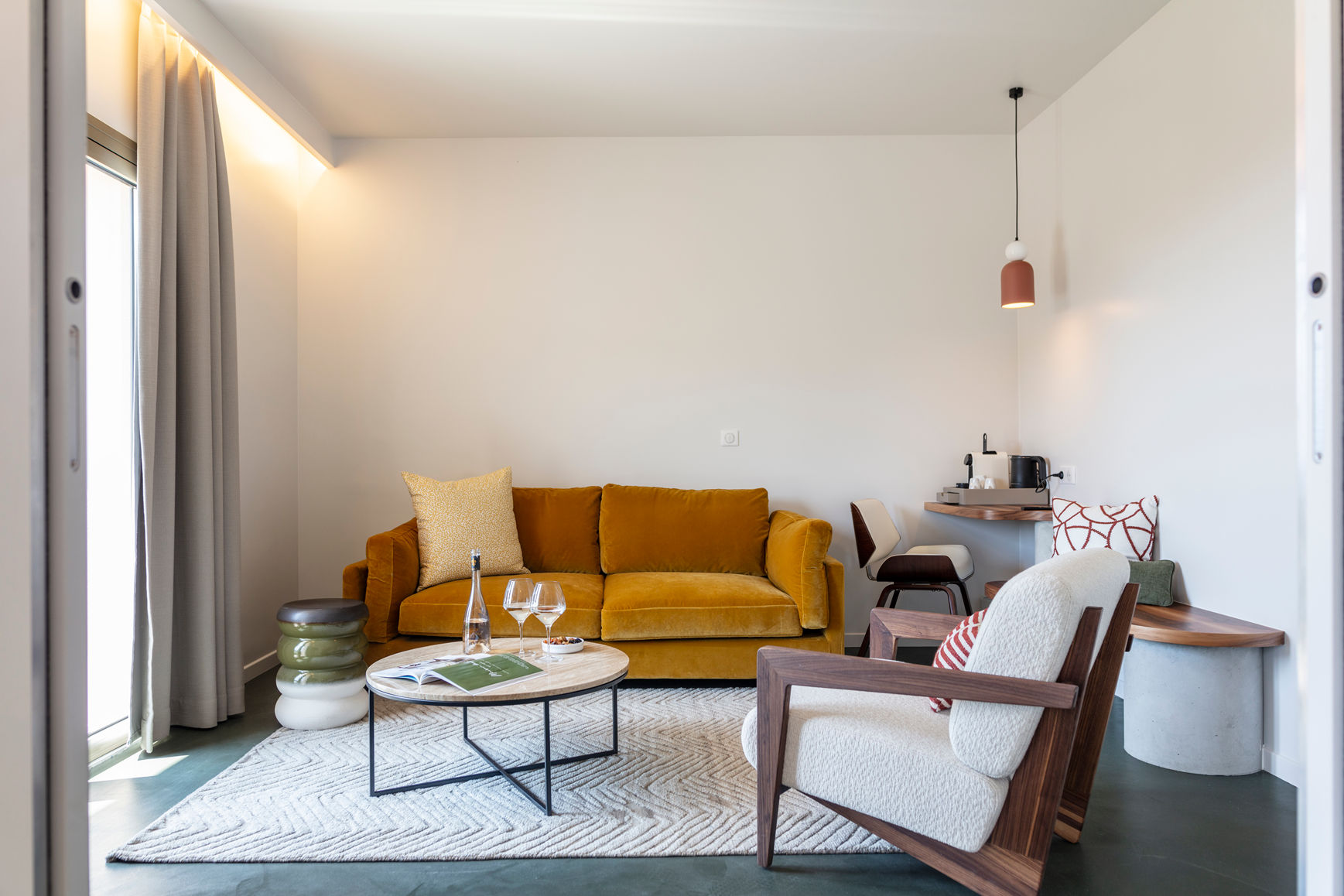 image Mustard sofa and a dining area in the natural light of the suite's open-plan living space